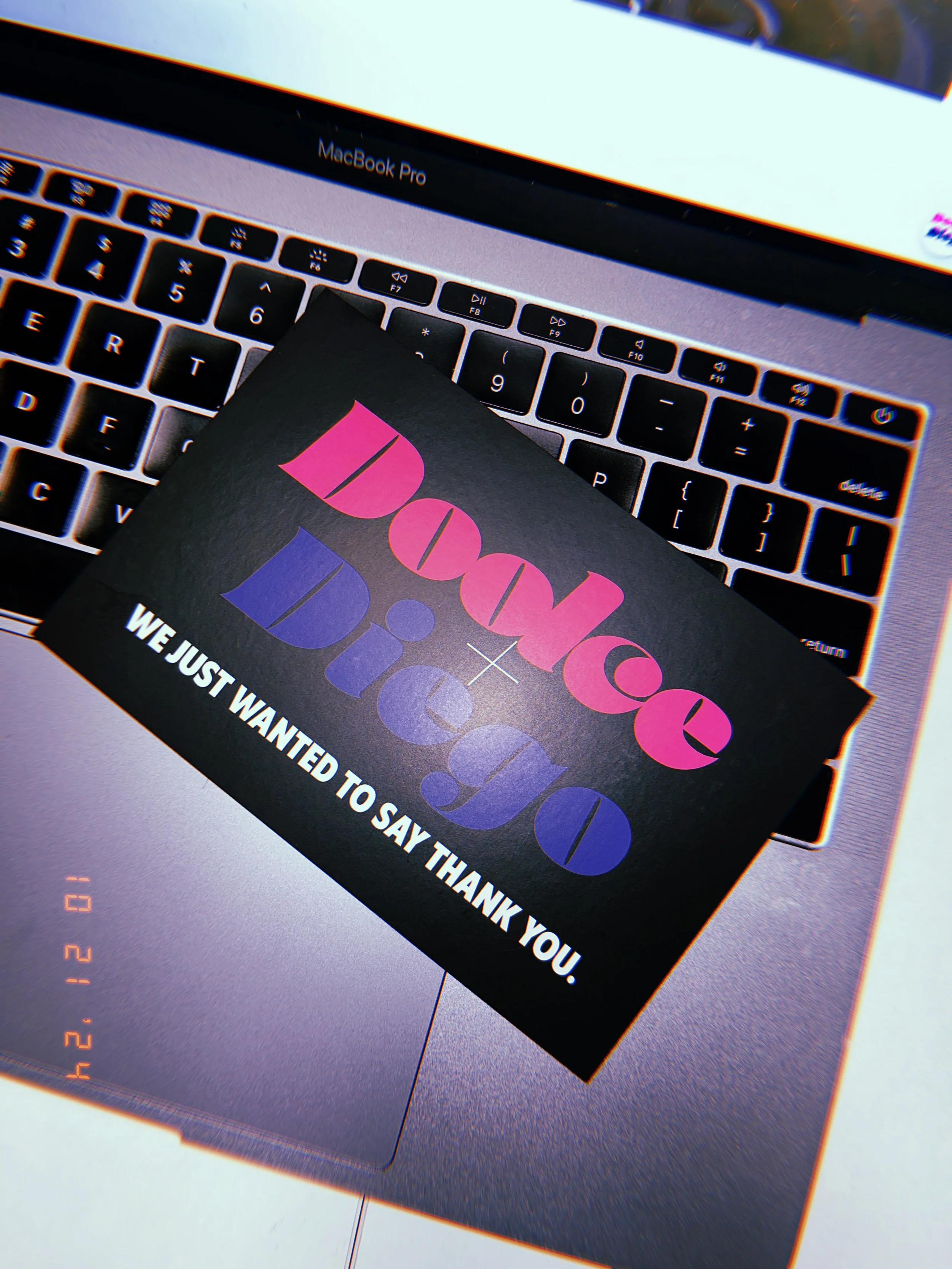 A black card with pink and purple text saying "I Don’t Duck, I Dodge" and white text reading "We just wanted to say thank you," resting on a silver MacBook Pro with a visible keyboard.
