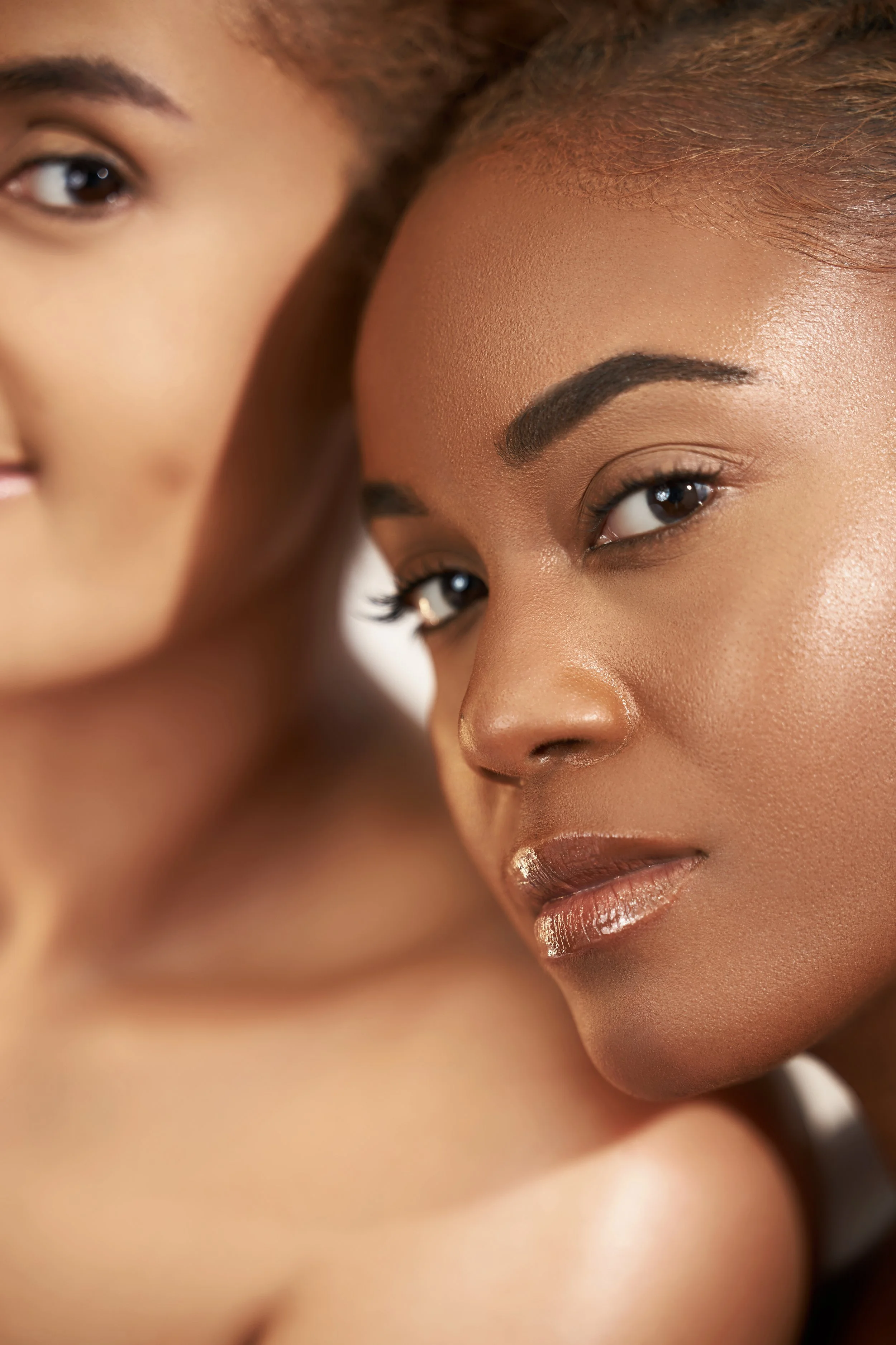 Close-up of two women with smooth skin, focusing on their faces and smiling expressions.