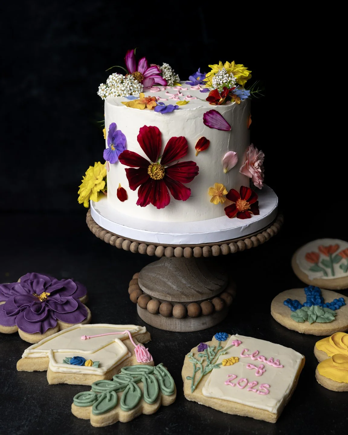 custom graduation cake decorated with fresh edible flowers and sugar cookies with buttercream florals