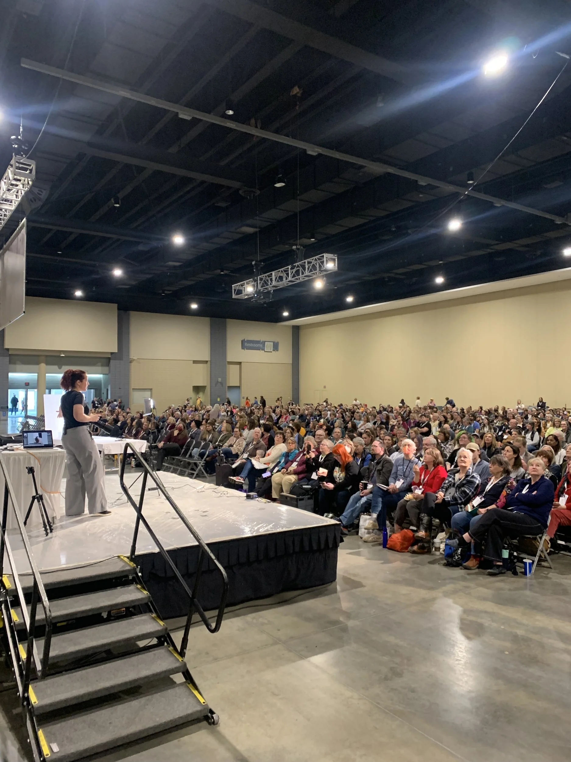 A person standing on a stage speaking in front of a crowd at a conference