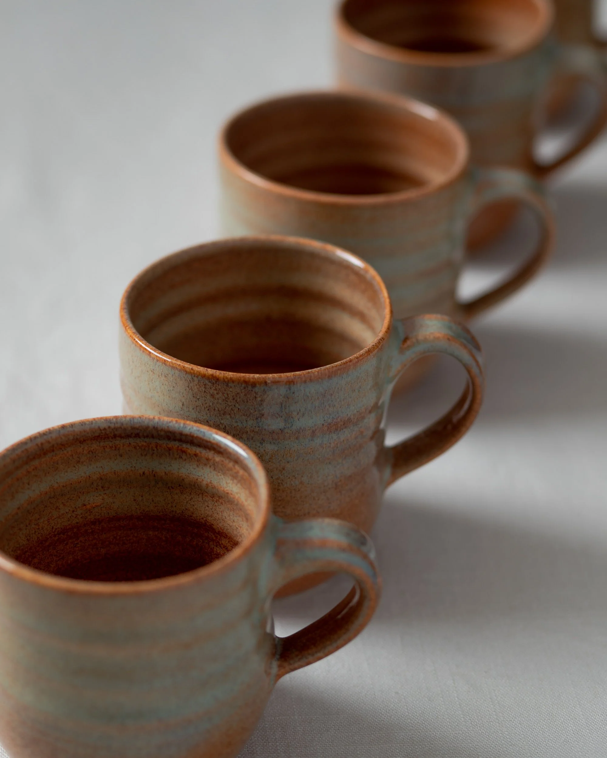 A row of identical ceramic mugs