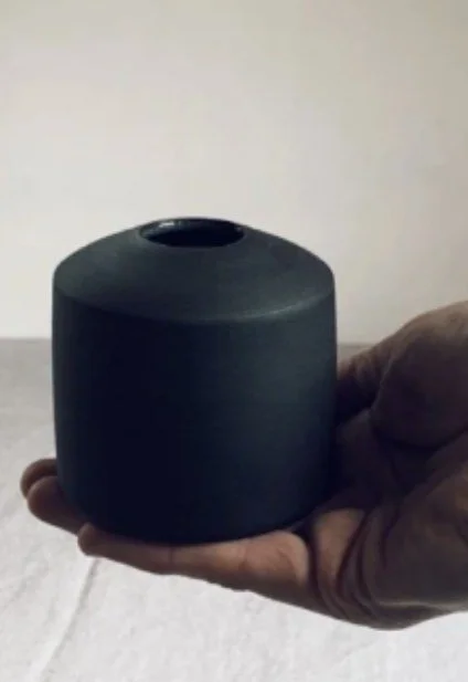 A hand holding a small vase