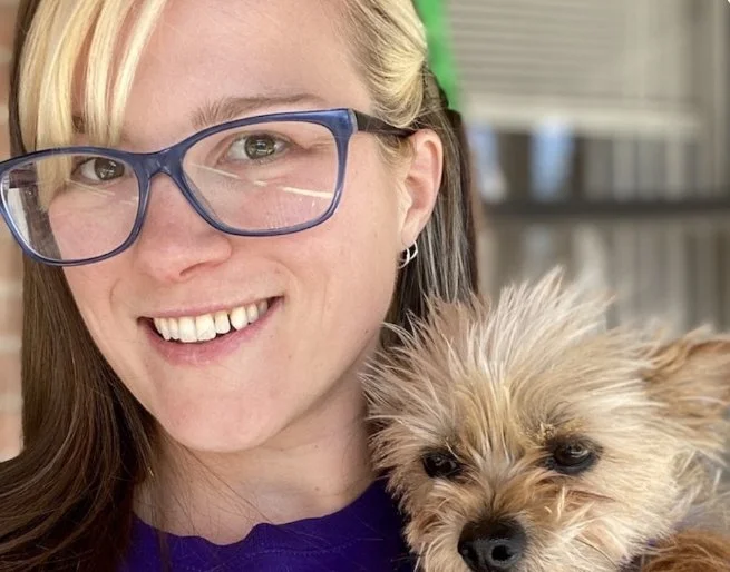 A person smiling with a dog looking over their shoulder