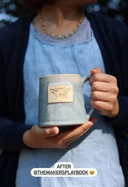 A person holding a mug with one hand on the handle and the other under the bottom