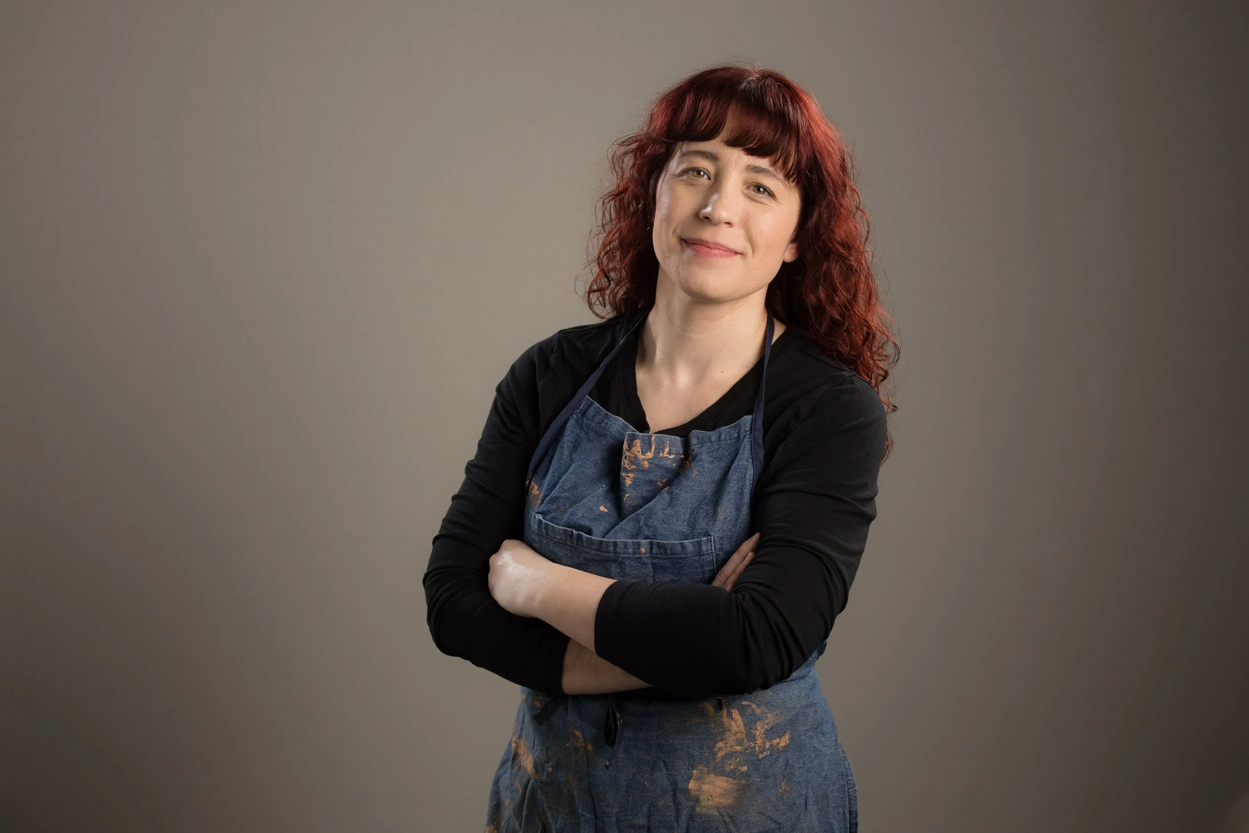 Rebecca with a small smile on her face and her arms crossed over her chest