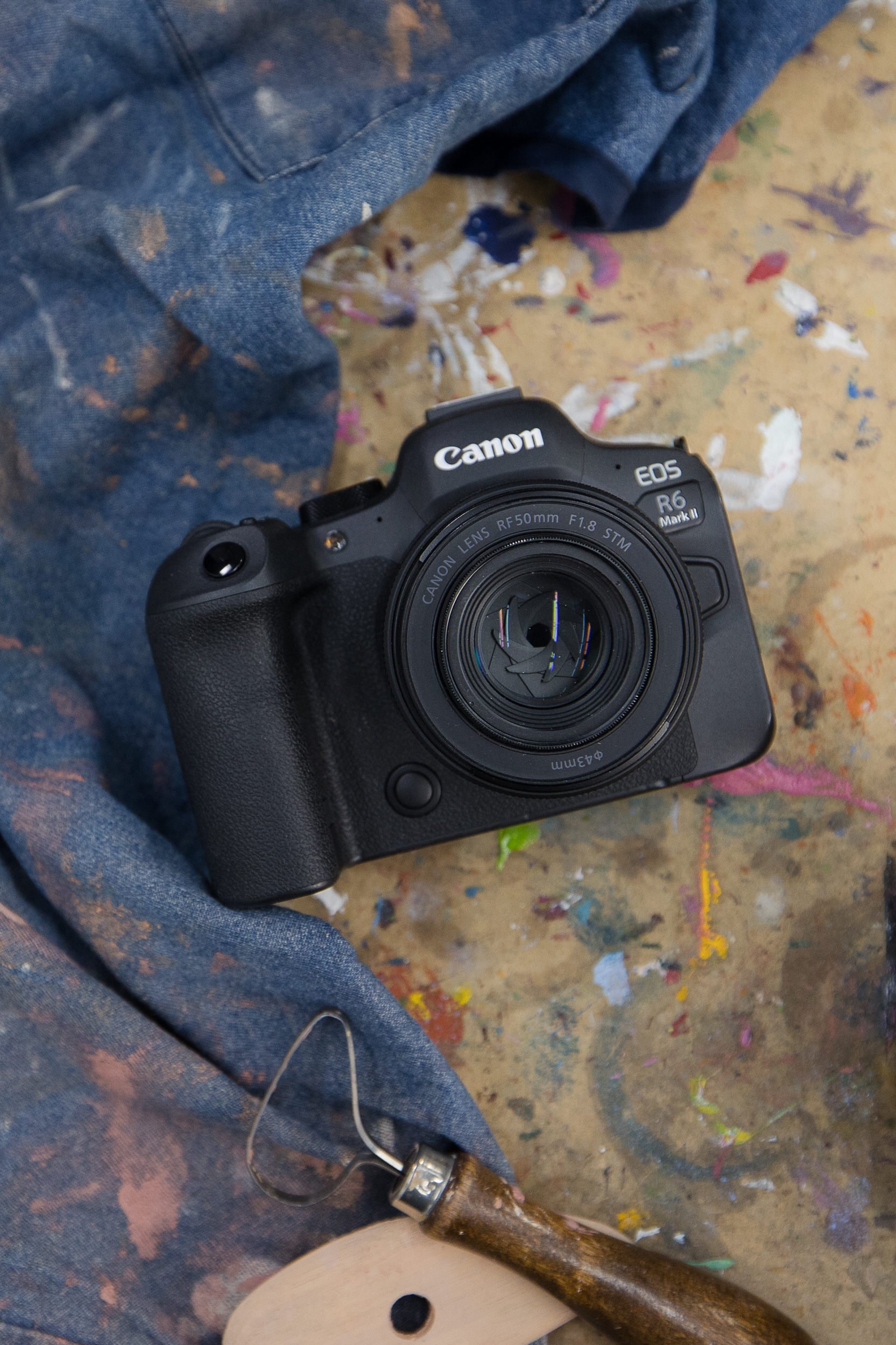 A camera on a paid covered table with pottery tools next to it
