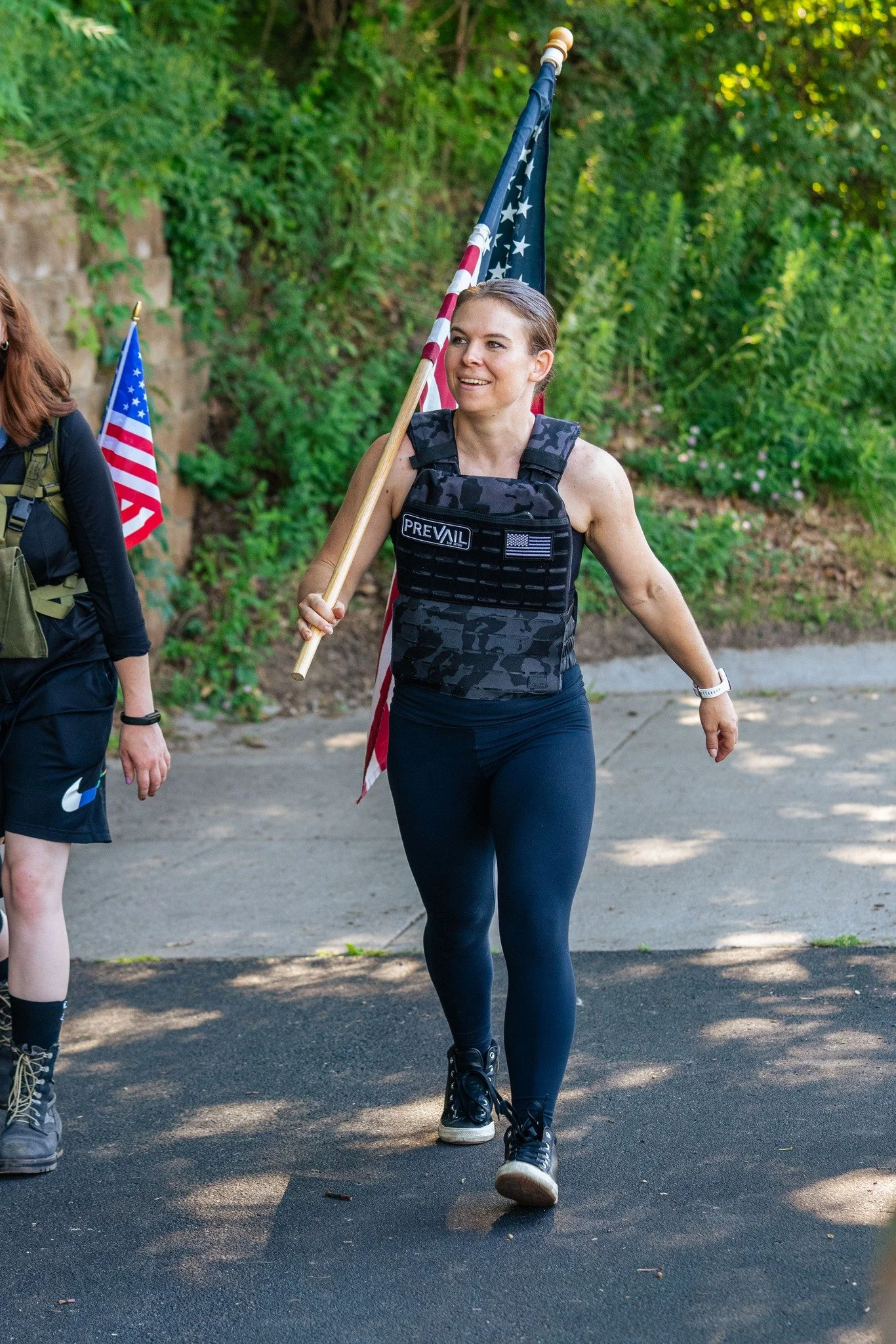 Person wearing a tactical vest holding an American flag