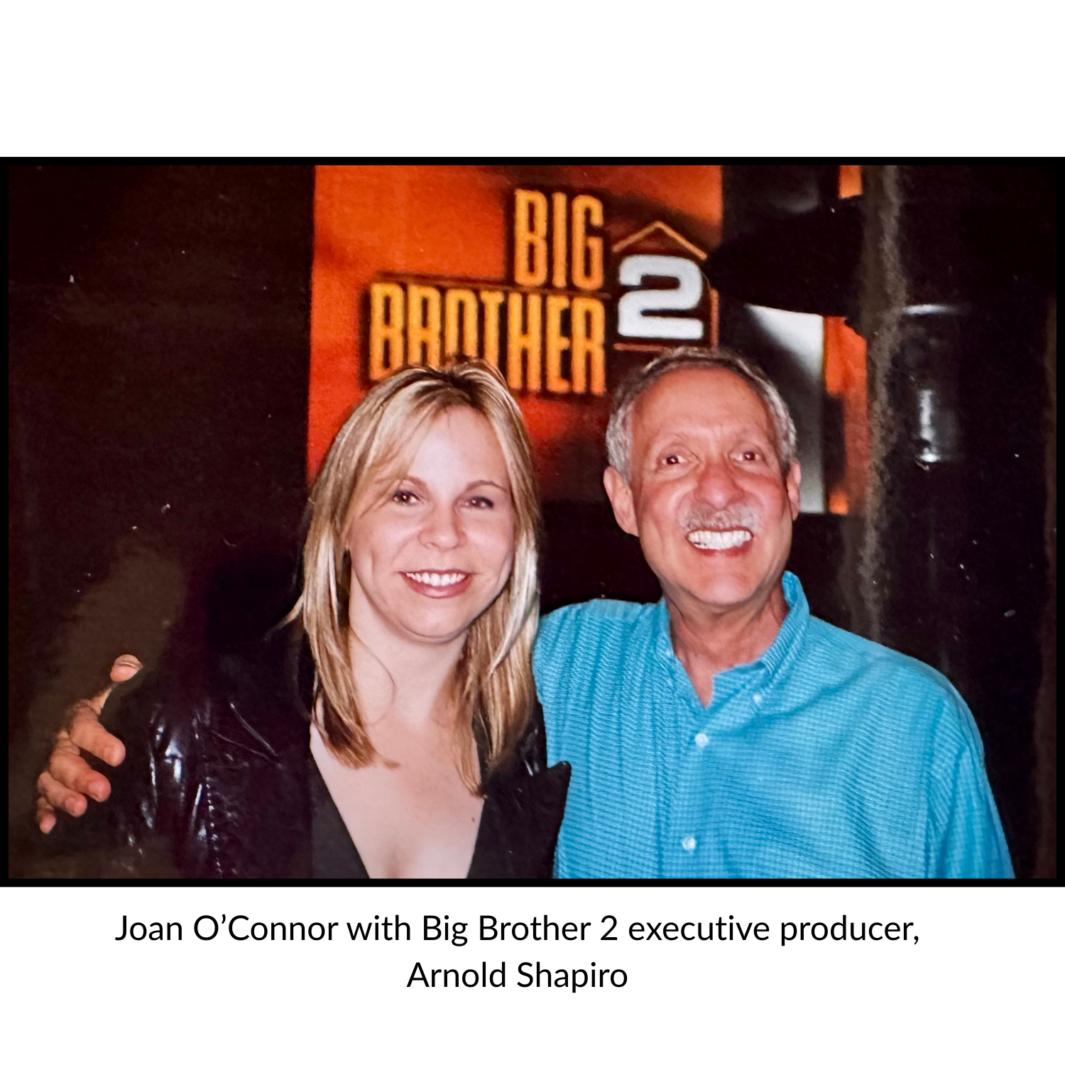 Joan O'Connor and Oscar winning documentary producer Arnold Shapiro posing together in front of a "Big Brother 2" sign.