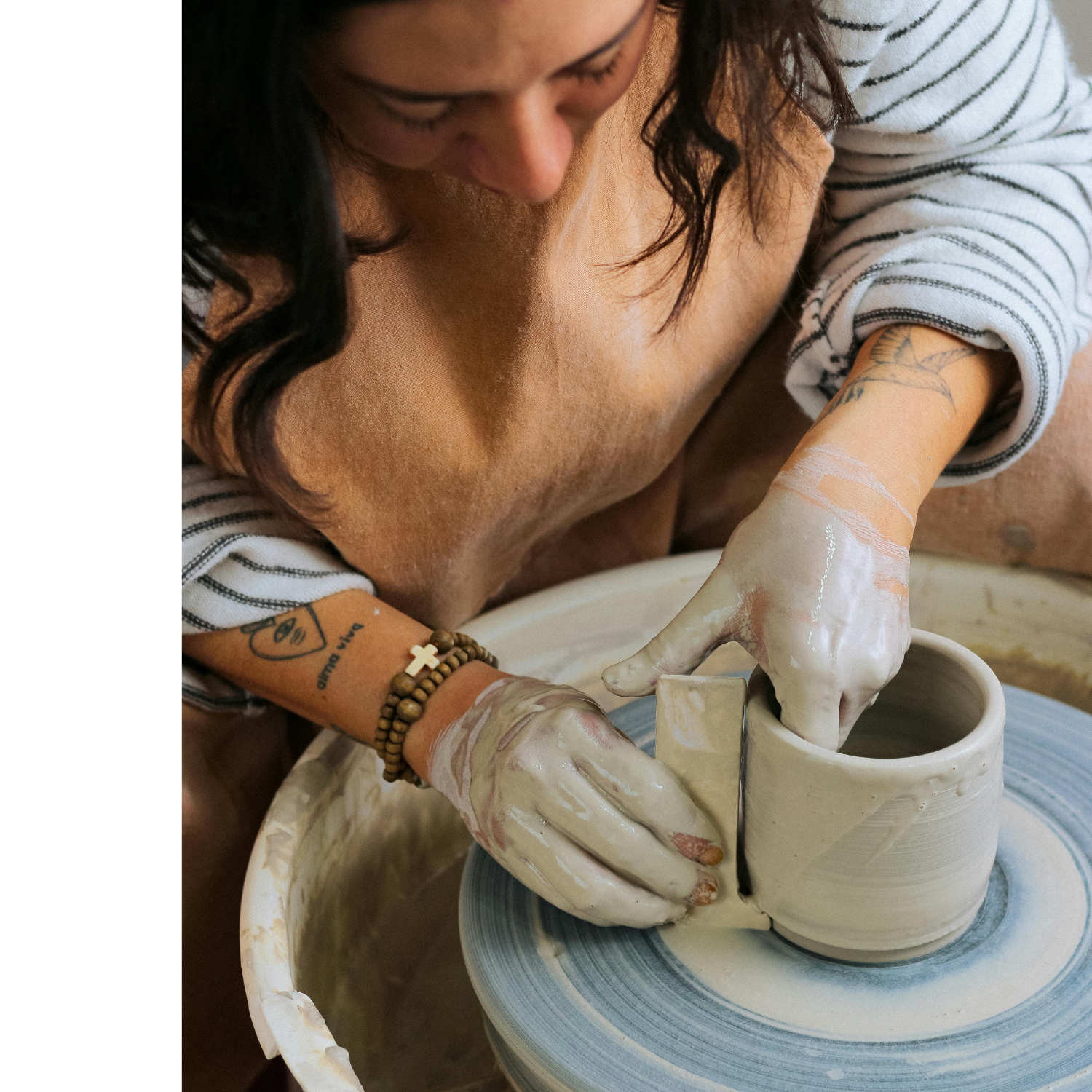 An Etsy seller using her hands to shape a pot on a spinning pottery wheel, with clay and tools visible.