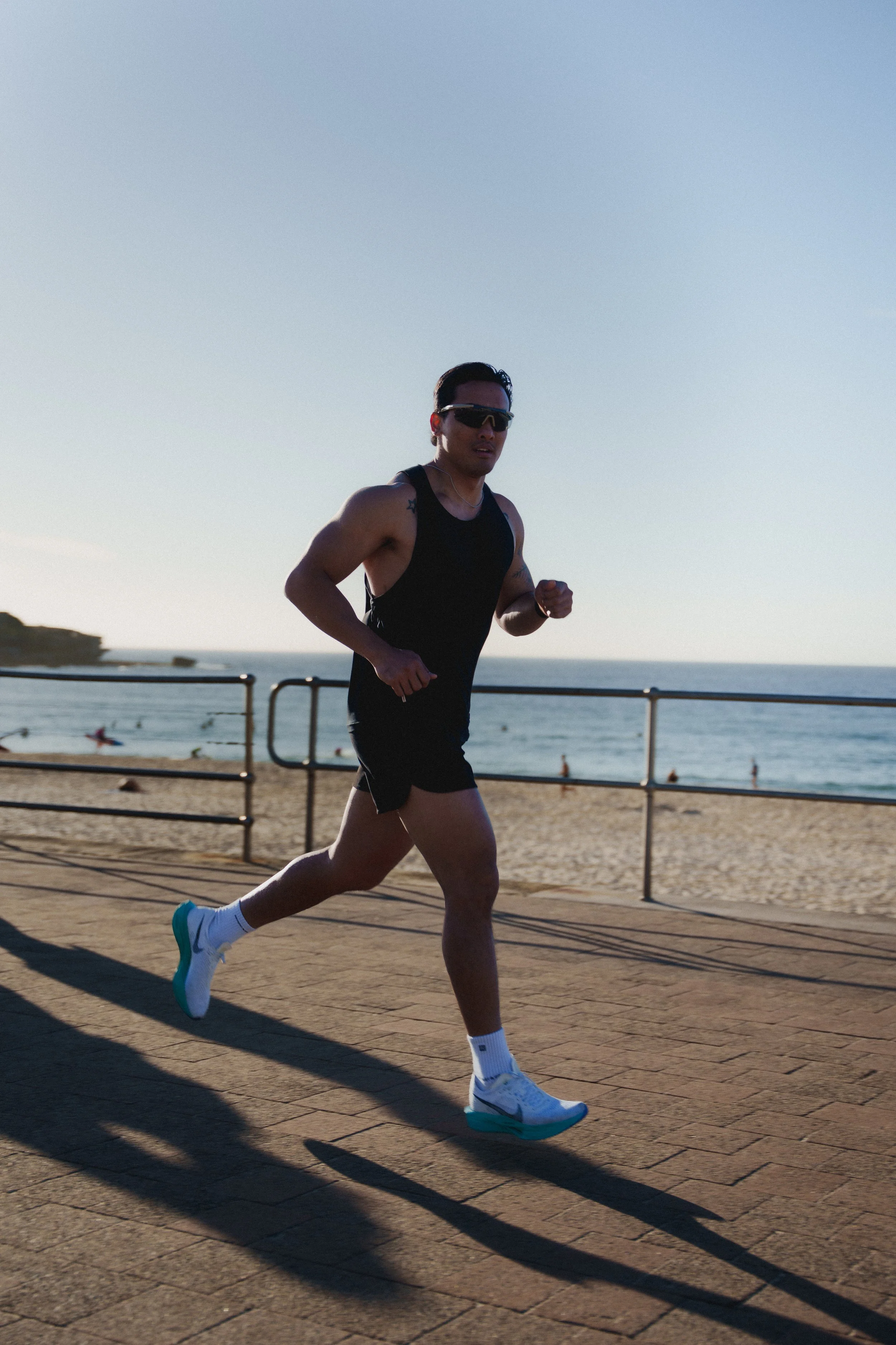 Man running on a promenade near the beach during sunset