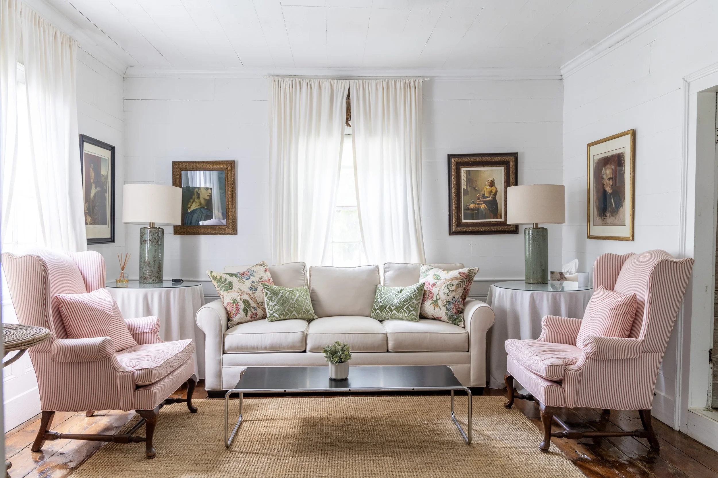 A sofa and pink arm chairs fill the living space at The Winn at the Round Top Motel in Round Top, Texas