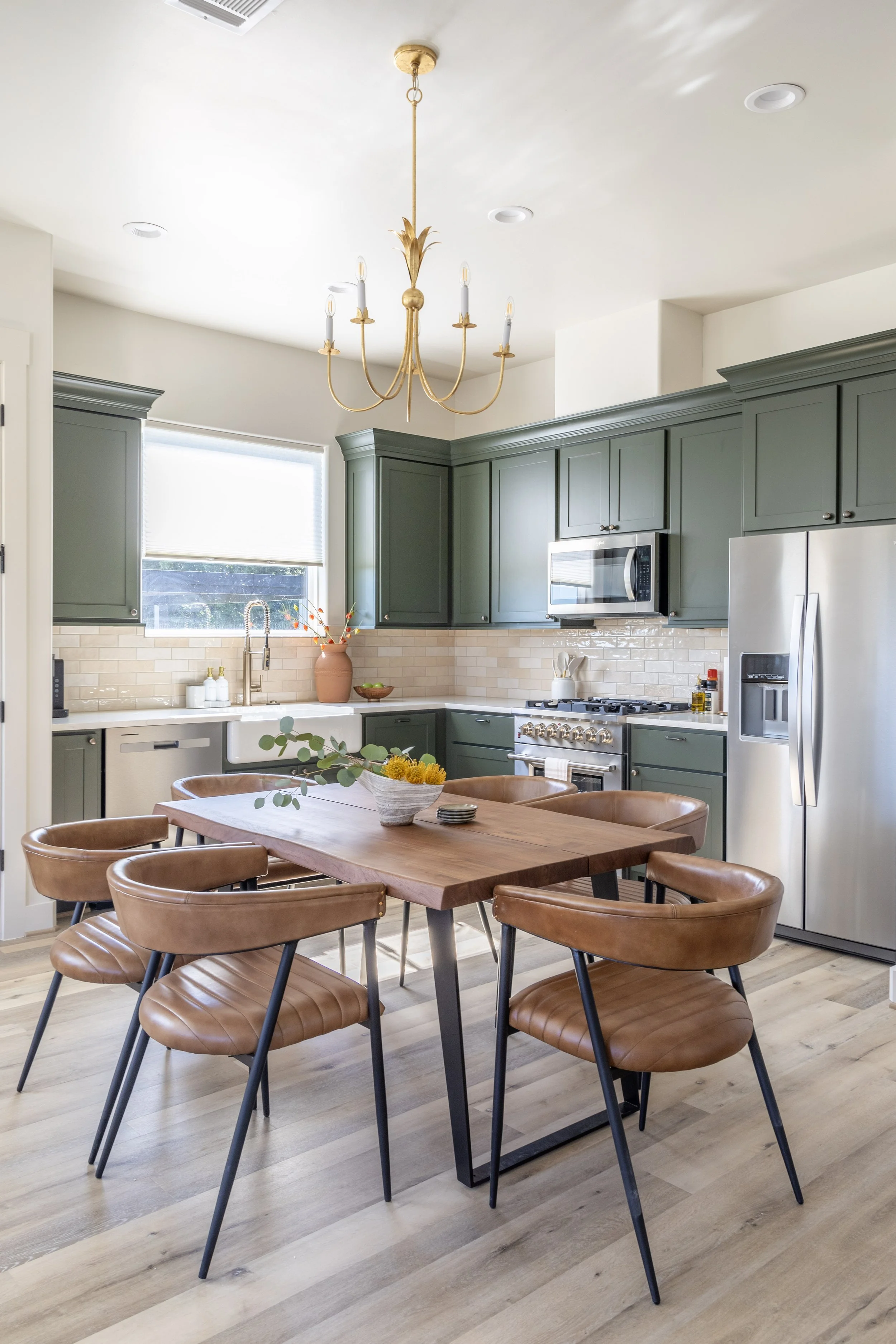 Green cabinets and a mid-century dining table fill the kitchen area in the Earth Retreat at Element Ranch in Round Top, Texas