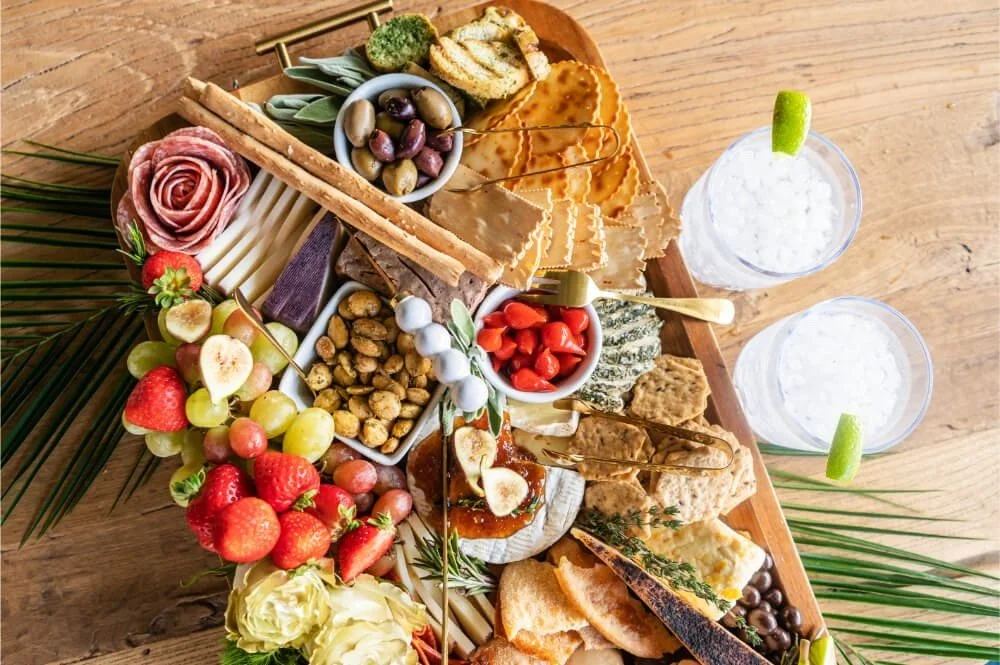 A platter of fruit, cheese, and crackers on a wooden table.