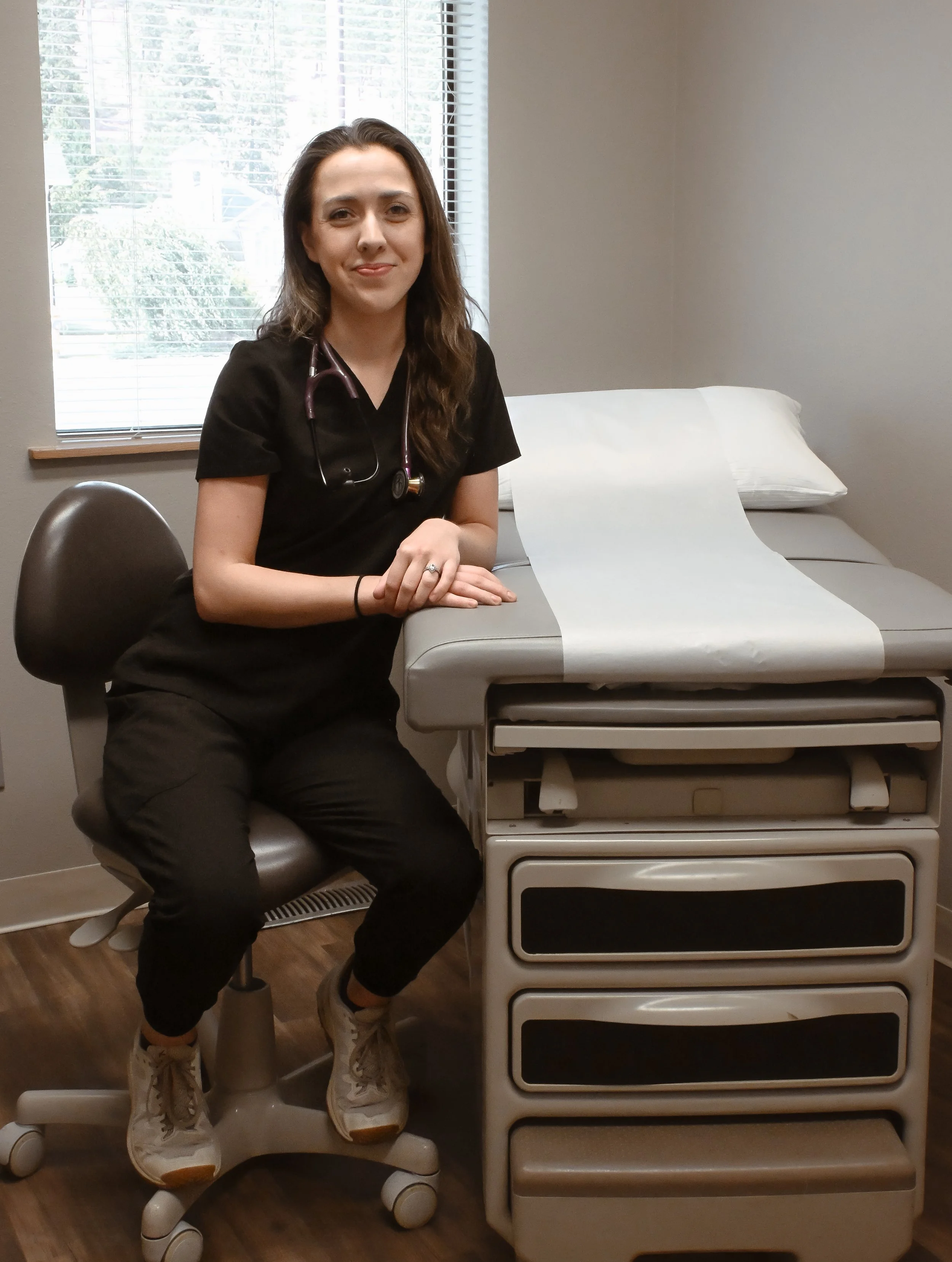 Hayden smiles at the camera while sitting in an exam room at Upper County Primary Care