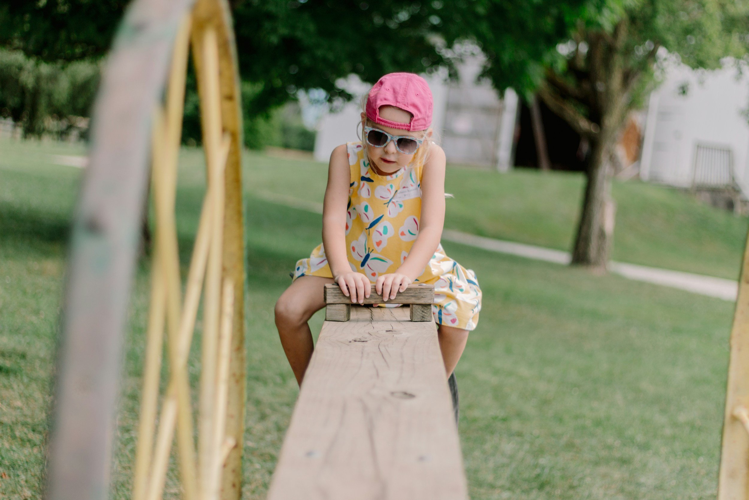 Child sitting on a wooden seesaw at the park, building balance and coordination