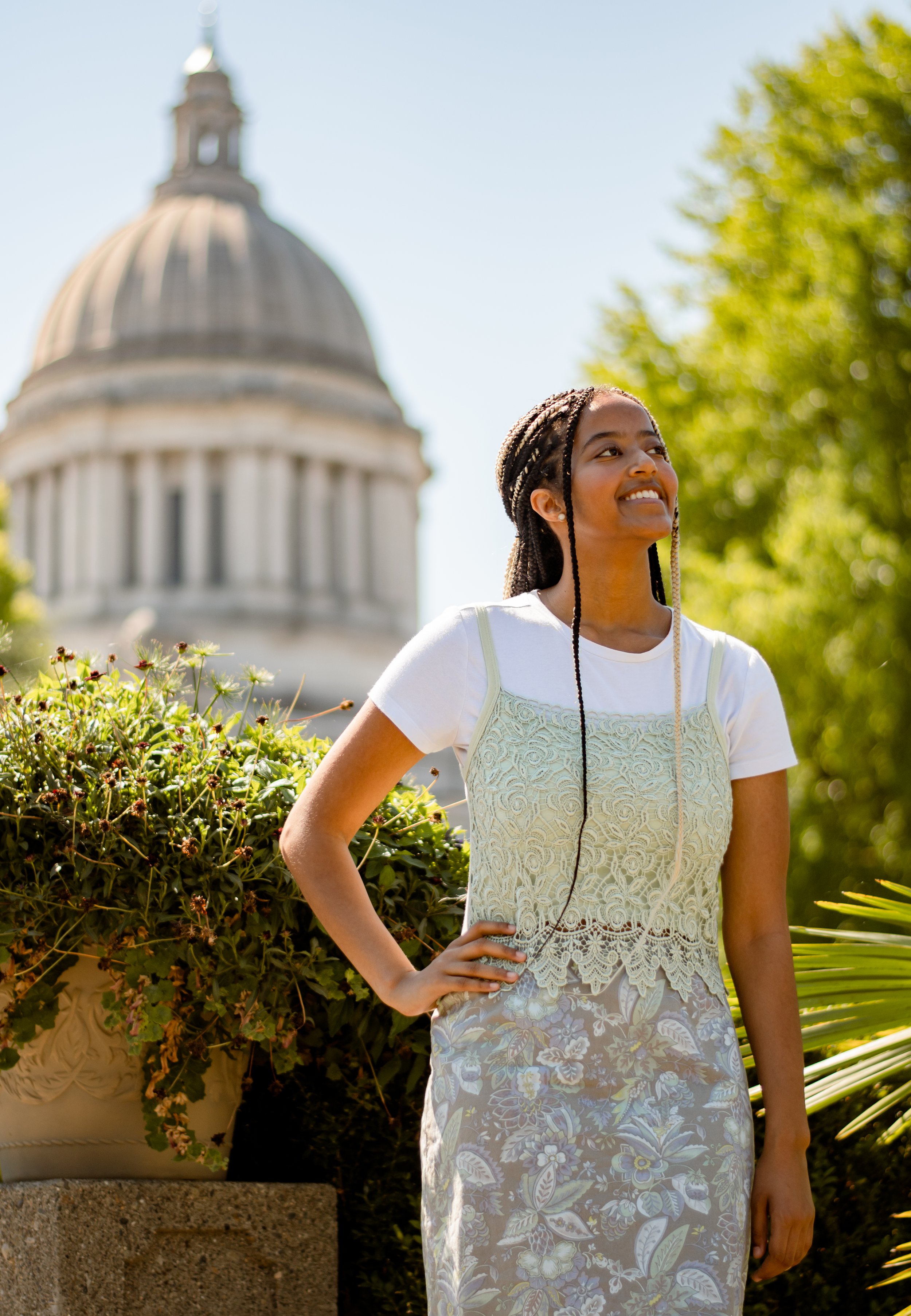 A young woman smiling with her hand on her hip in front of the Washington State Capitol Building in Olympia.