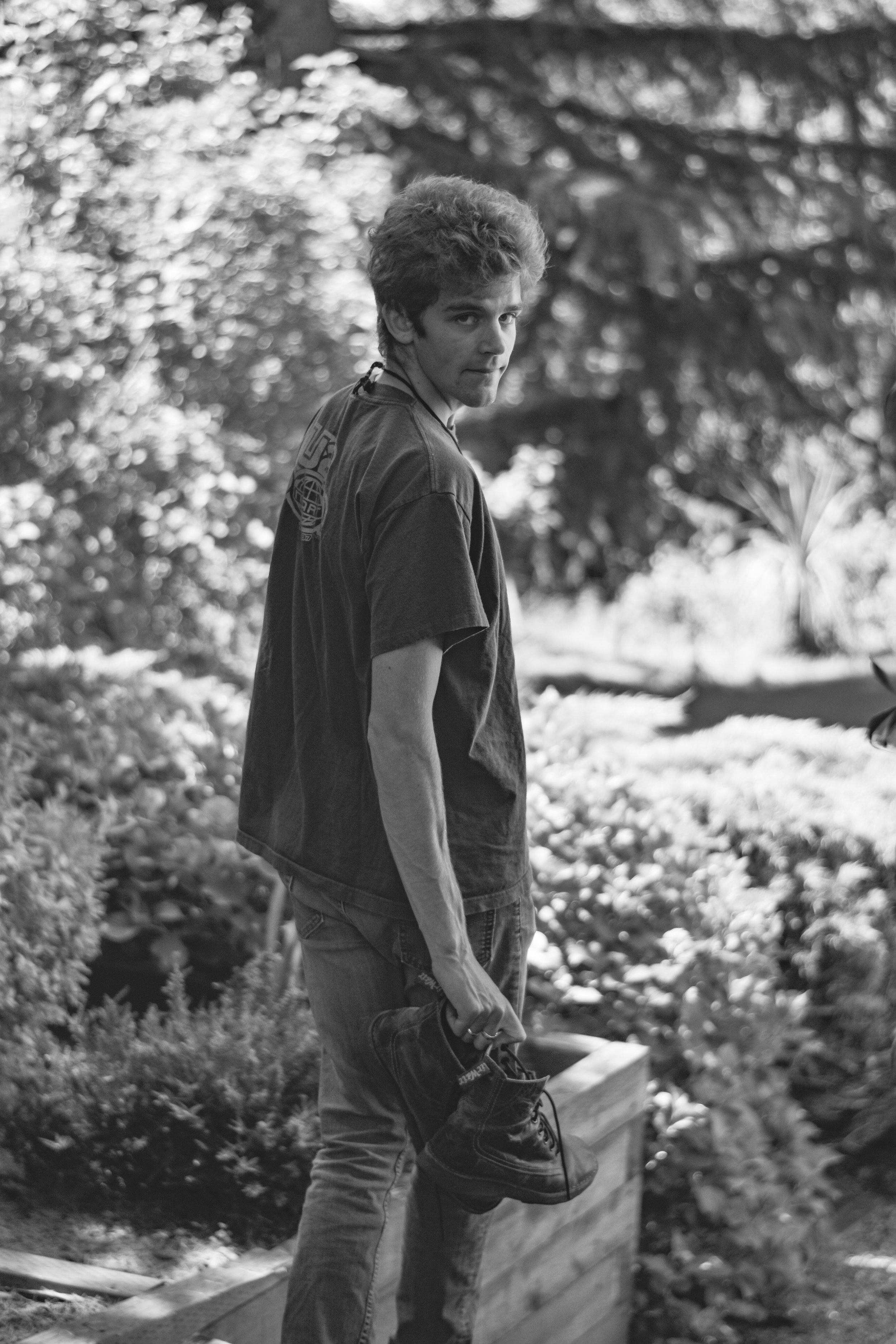 A young man walking away from the camera and looking back with a soft smile, pictured in black and white.