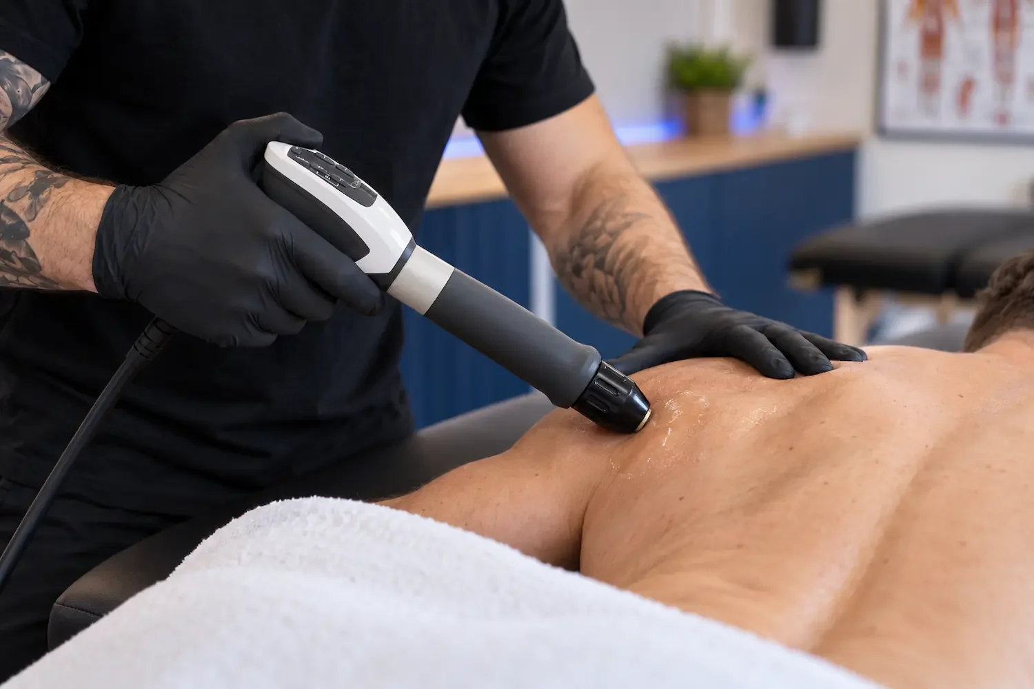 Practitioner applying radial shockwave therapy to a client's upper back at Biohack Cryo & Wellness in Woodland Hills
