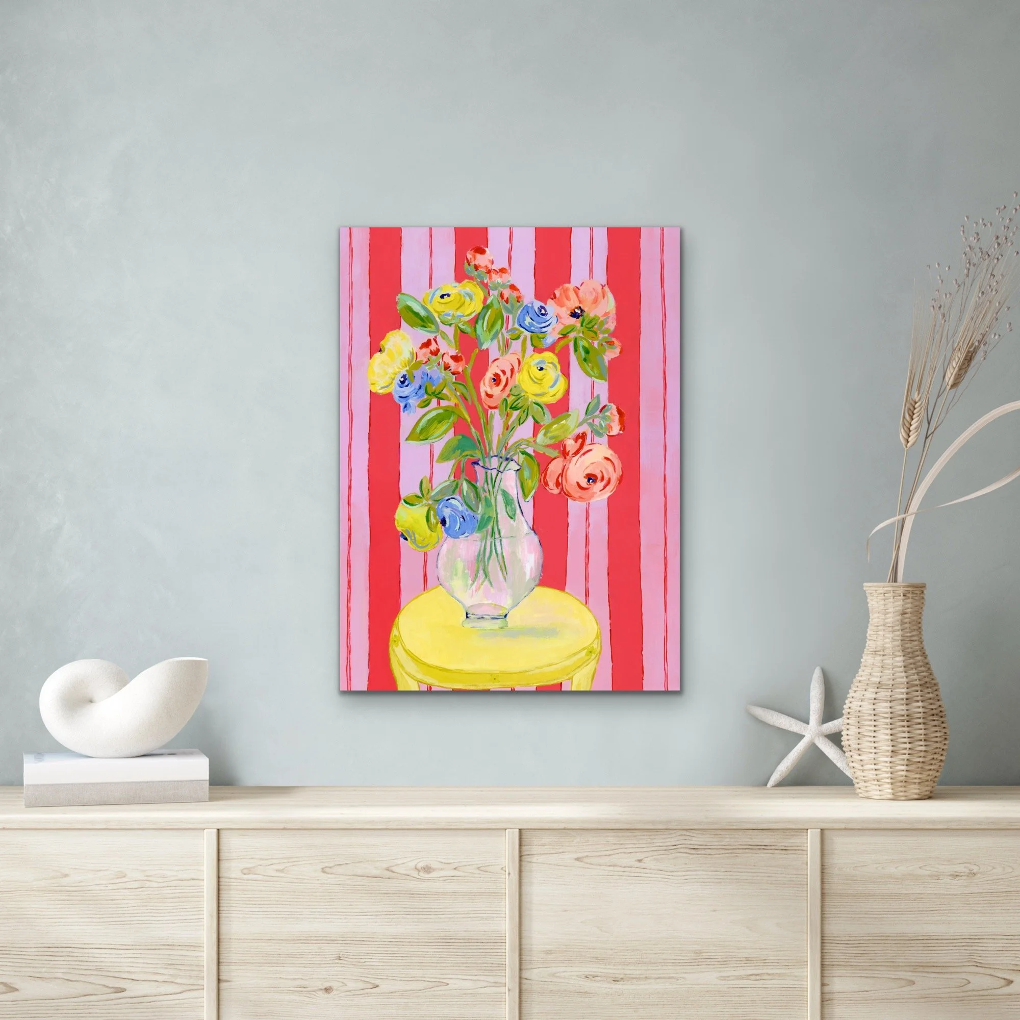 Grand Arrangement of a large bouquet of ranunculus in a transparent vase on bright yellow table. Red and lavender background.