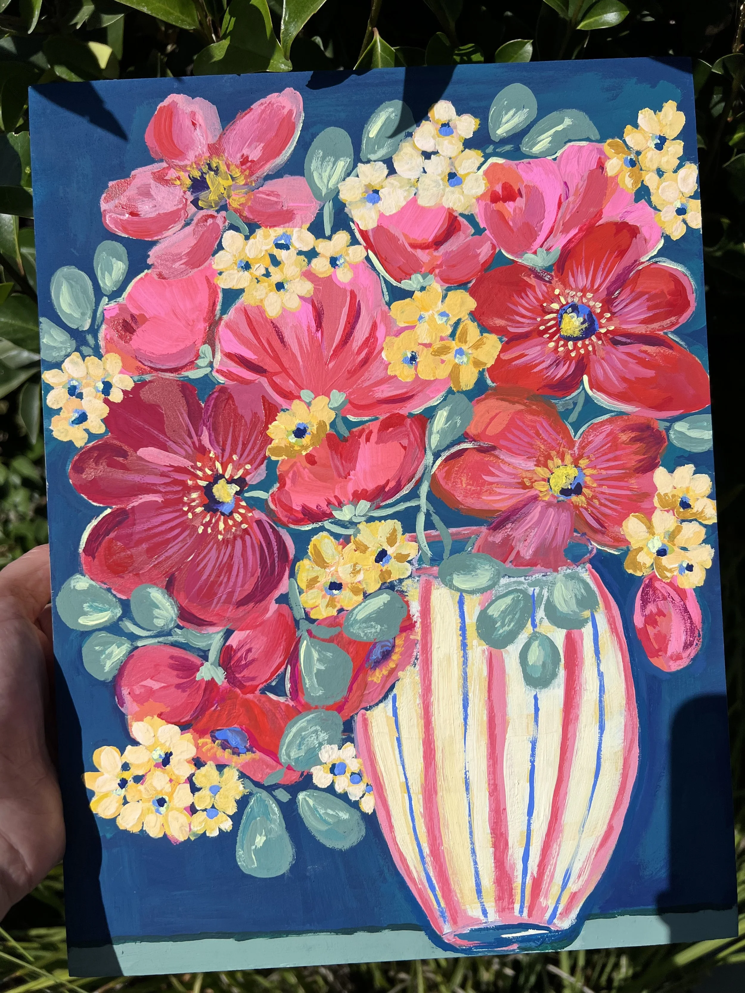 Bold pink & red poppies burst from a playful striped vase on a deep blue background.