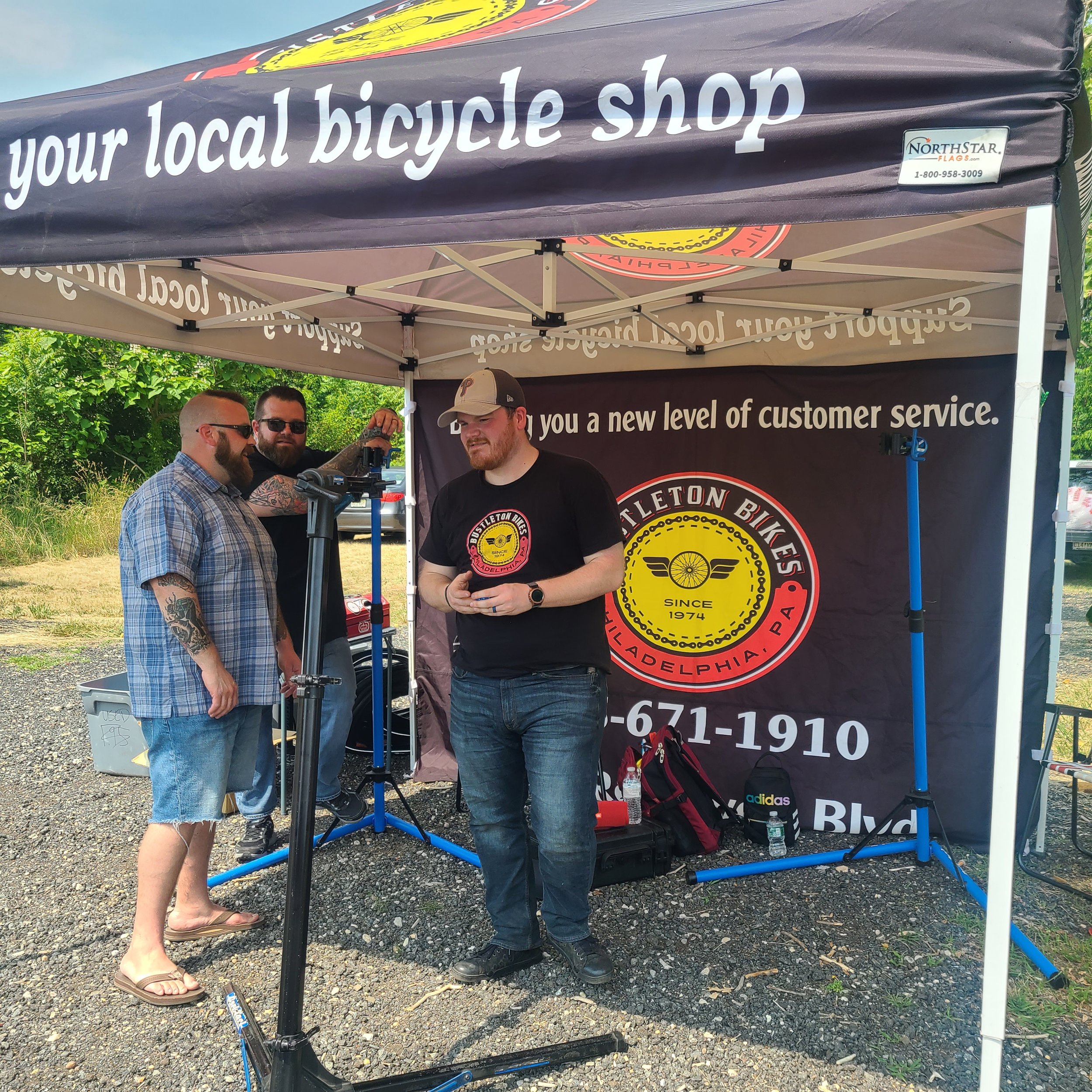 Bustleton Bikes mechanics under a branded event tent at the American Cancer Society bike-a-thon.