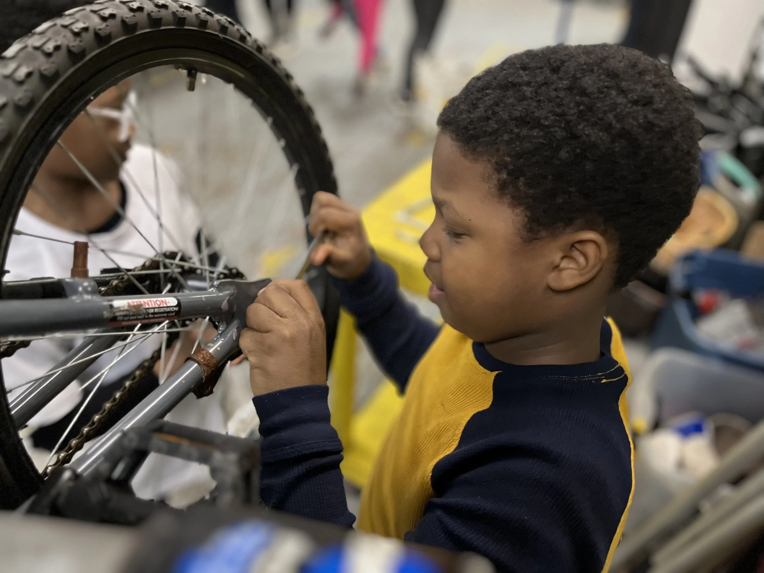 A youth participant learns mechanical skills by working on a bicycle frame during a skills clinic.