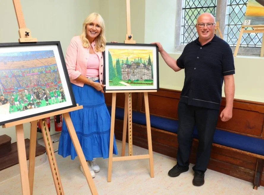 Artist Alan Tarpey standing with Miriam O'Callaghan and two pieces of his artwork