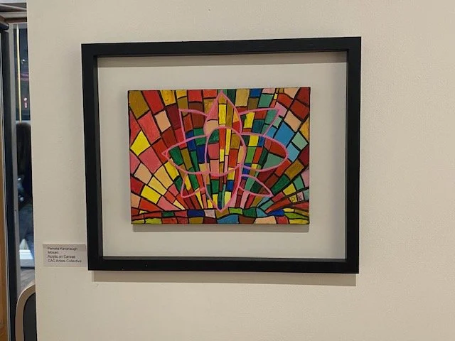 Framed abstract mosaic painting with a vibrant, stained-glass-like background of red, yellow, pink, blue, and green rectangles. A bright pink, stylized floral or atomic symbol is centered over the mosaic.