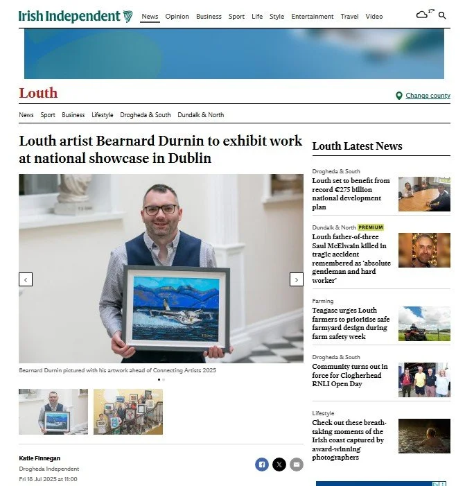 A smiling artist, wearing glasses and a vest over a patterned shirt, holds up a framed painting of a boat on a blue body of water with distant mountains under a vibrant sky, with a headline above about his upcoming exhibition.