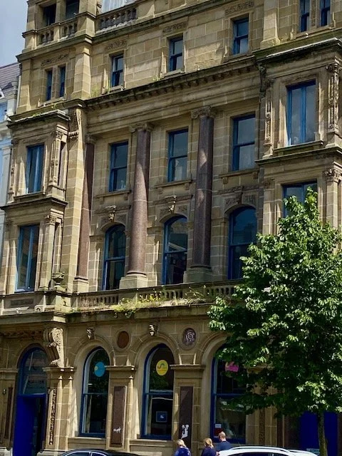 A detailed, ornate, multi-story stone building with arched windows and decorative columns.