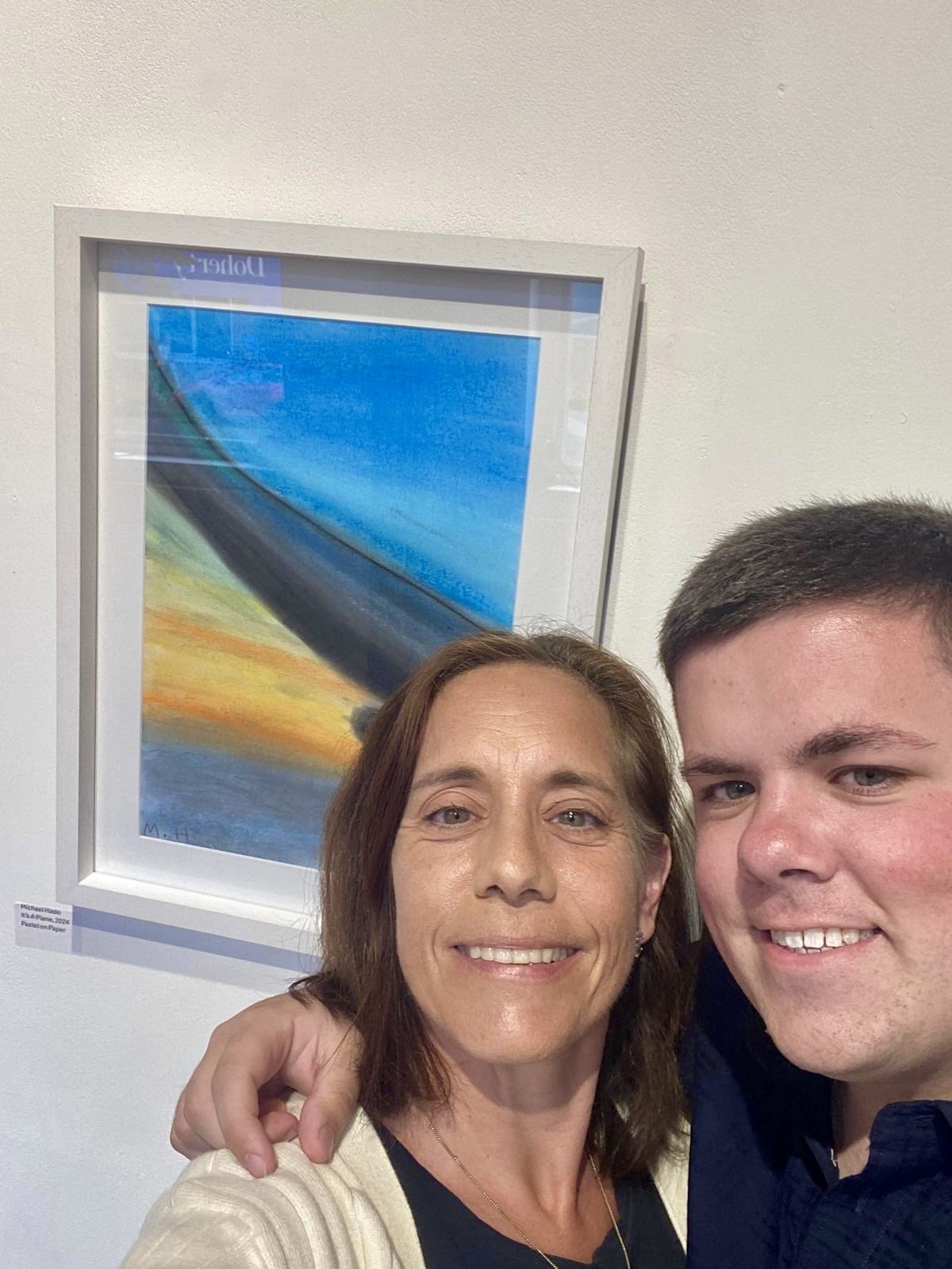 Artist Michael Hade and Joyce Hade taking a selfie in front of Michaels artwork "its a plane" hanging in the Atypical Gallery.