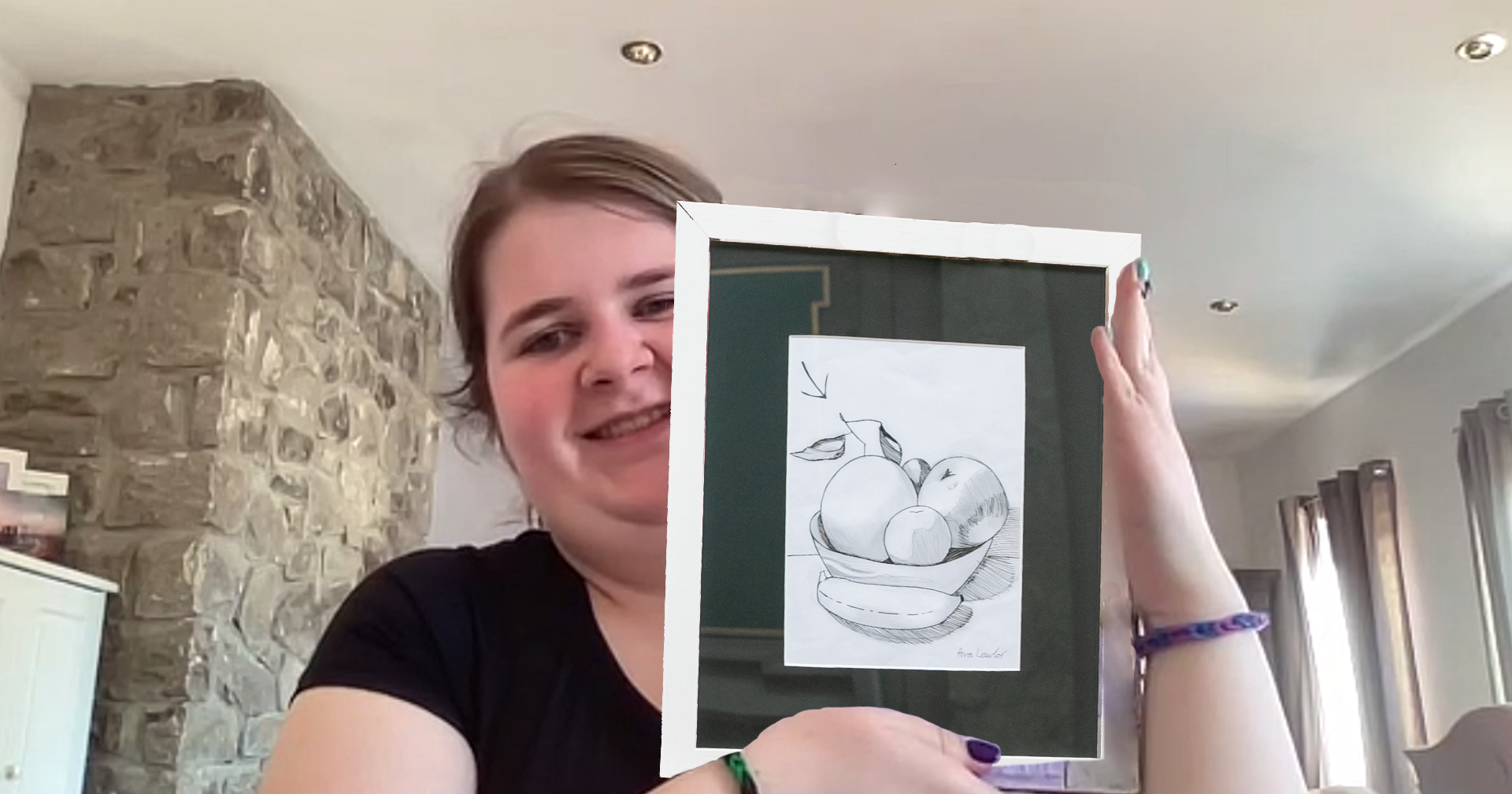 A person holds a framed sketch of a still life featuring fruit in a bowl.