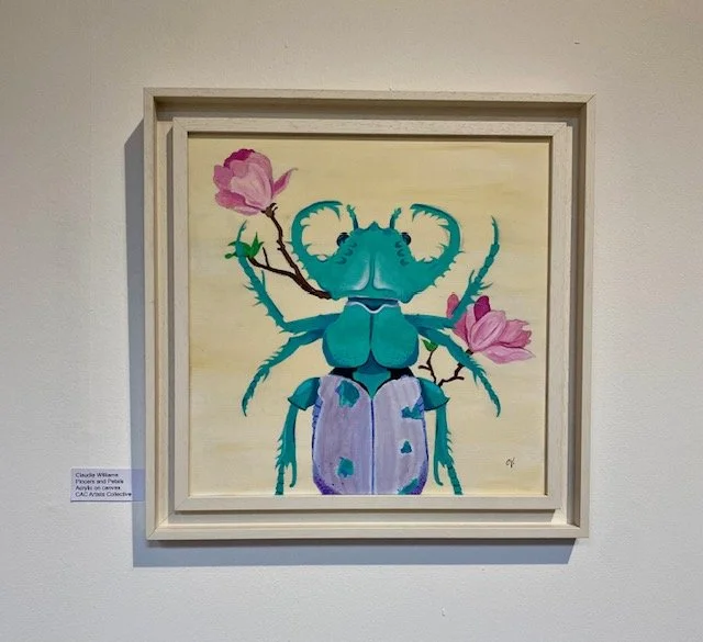 A vibrant turquoise beetle with striking horns is depicted in a whimsical painting. The beetle is adorned with light purple that has textured blue patches. Delicate pink magnolia blossoms branch out from behind the insect, framing its head and body a
