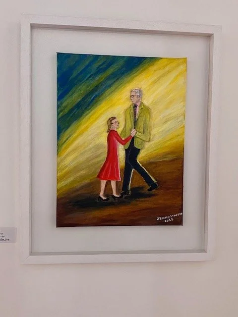 An acrylic painting in a white frame depicts a young person in a red dress and an older person in a lime green jacket holding hands and dancing. The background is a gradient of vibrant yellow and blue brushstrokes.