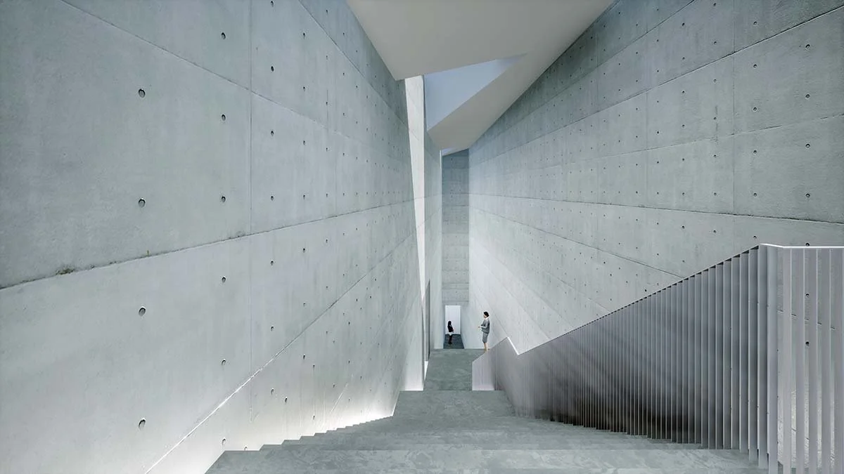 Modern building interior with high concrete walls, a staircase, and two people standing at the top.