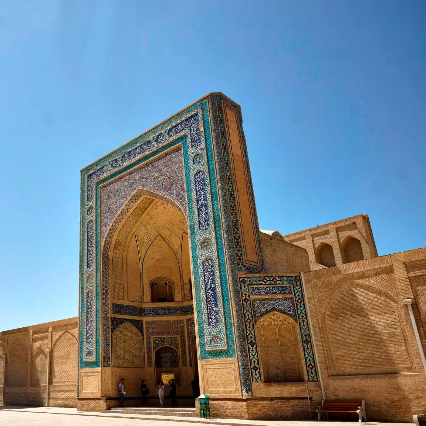 Historical building with intricate tile work and large archway entrance under a clear blue sky.