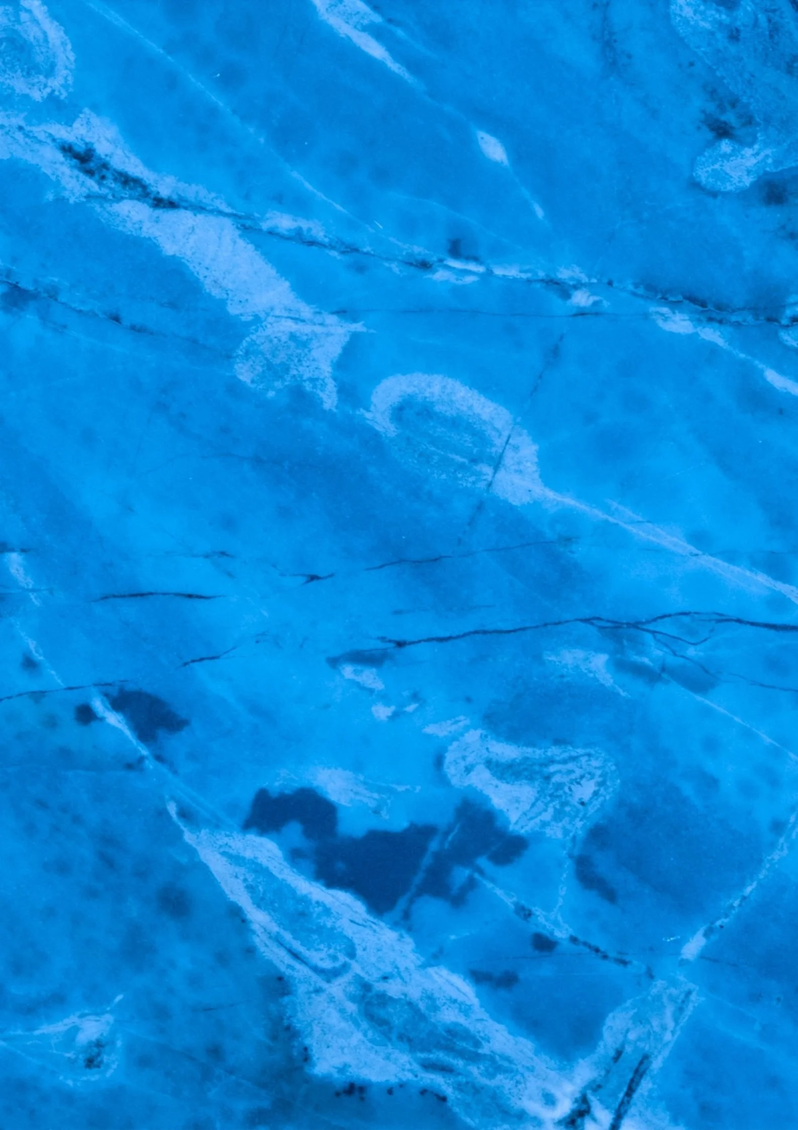 Close-up of a blue ice surface with cracks and patterns.
