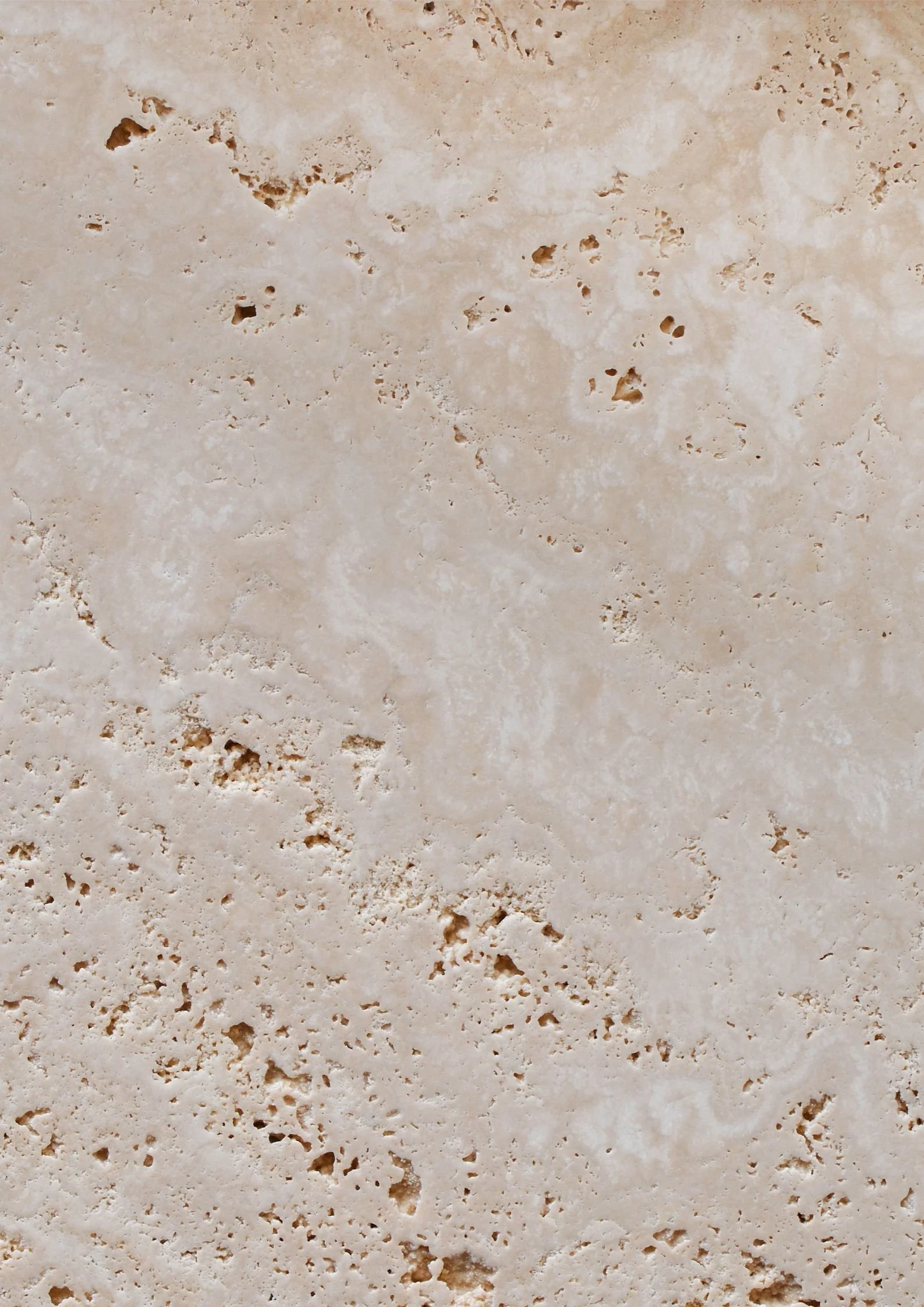 Close-up of beige and tan textured stone surface with small holes and natural patterns.