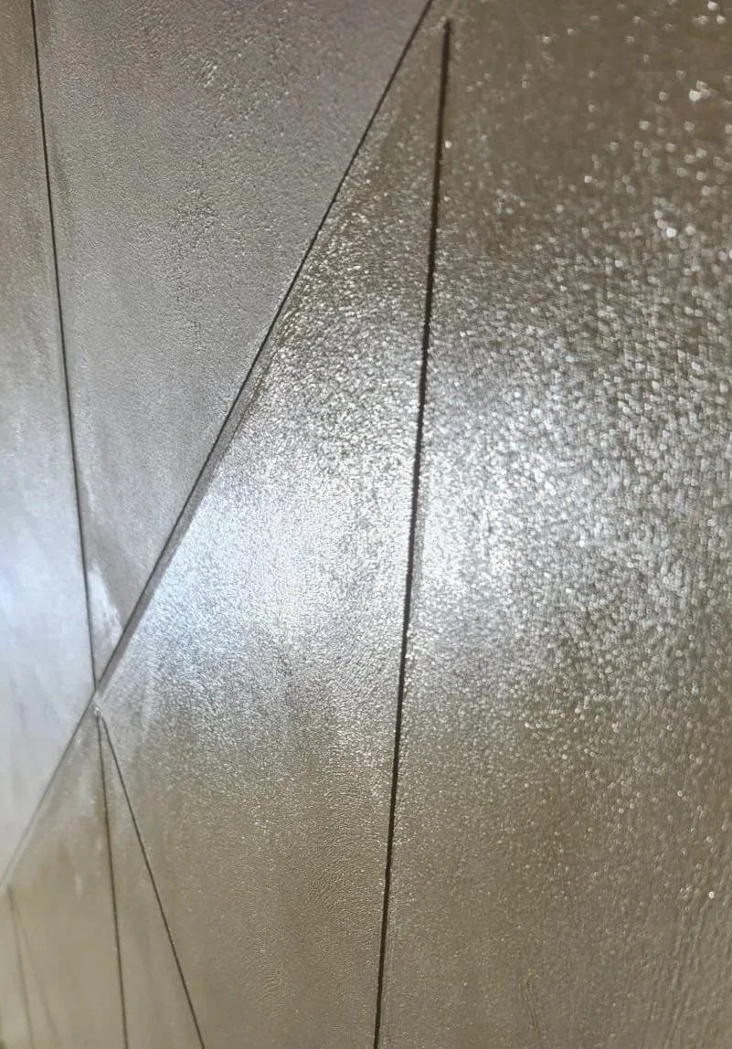 Close-up of metallic textured wall or ceiling with visible seams and speckled finish.