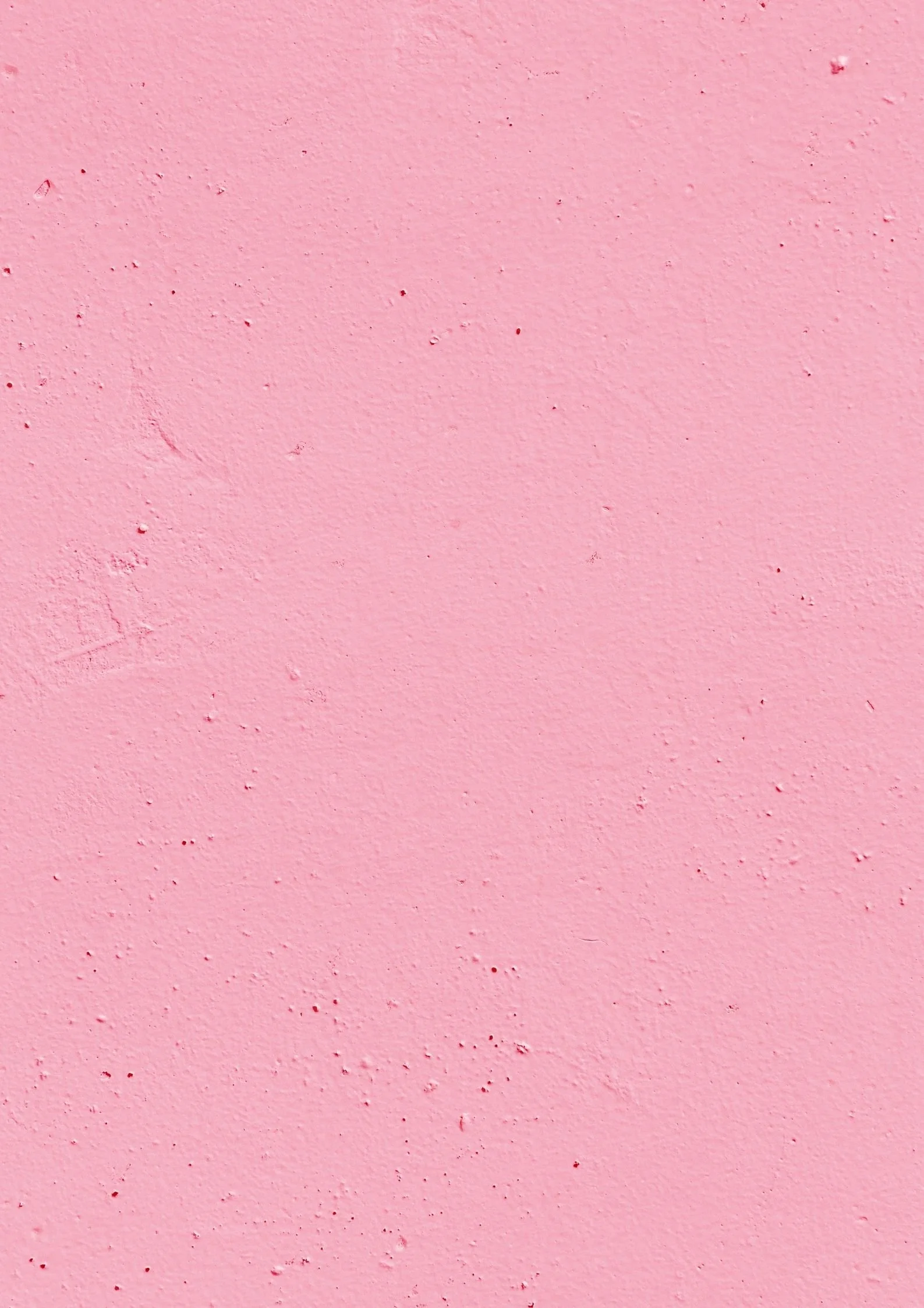 Close-up of a pink textured wall with small imperfections and paint chips.