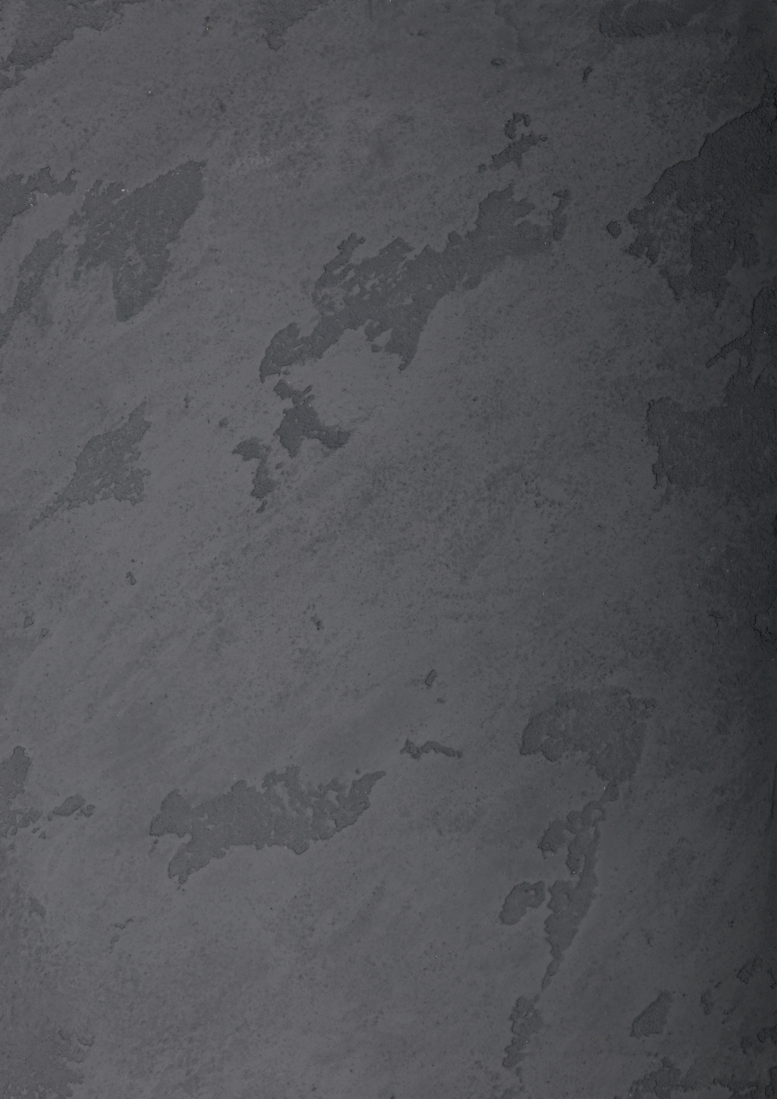 Close-up of a dark gray, textured surface with irregular patches of peeling paint or coating.