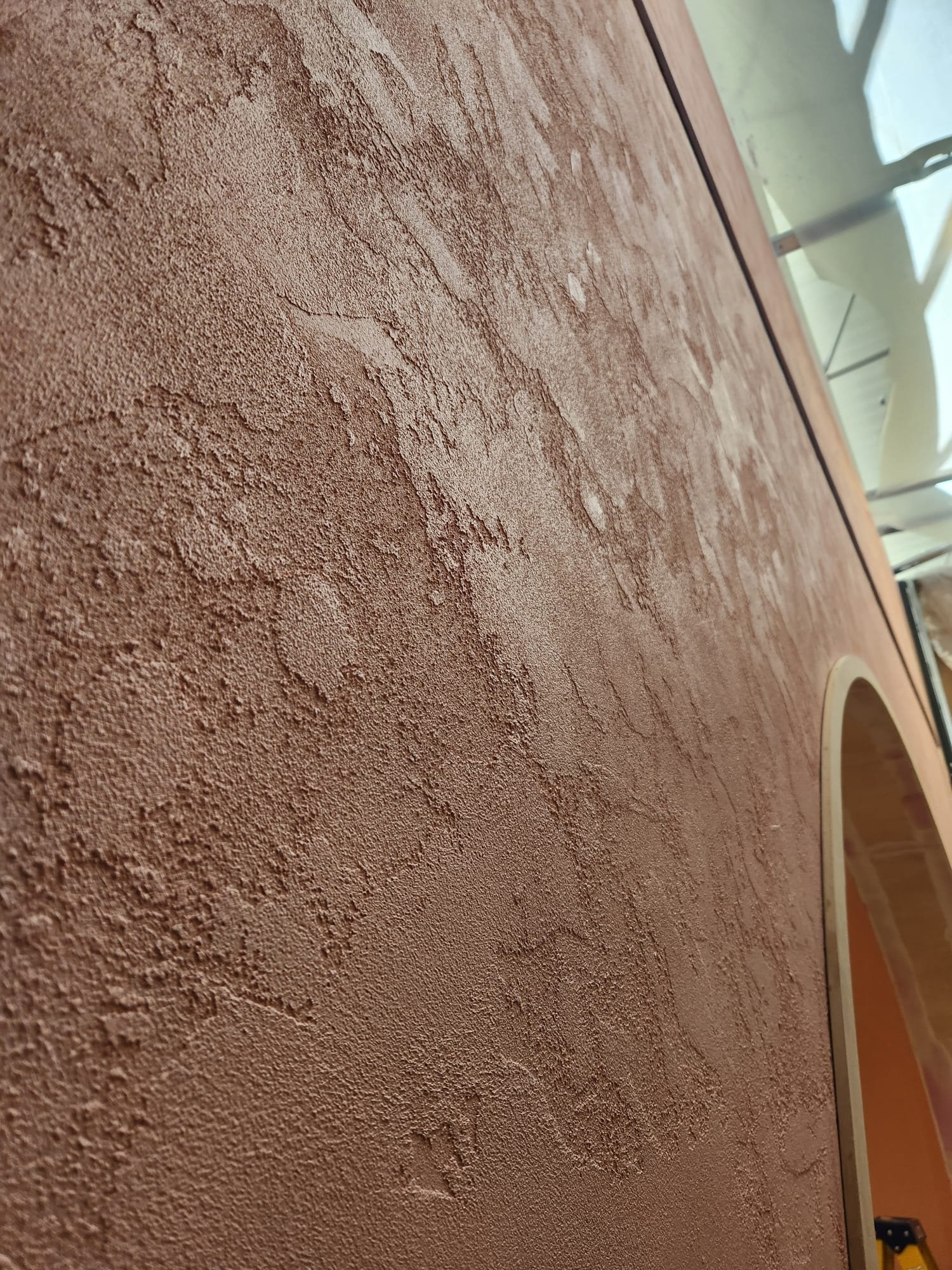 Close-up view of a textured brown wall or surface with a rough, uneven pattern.
