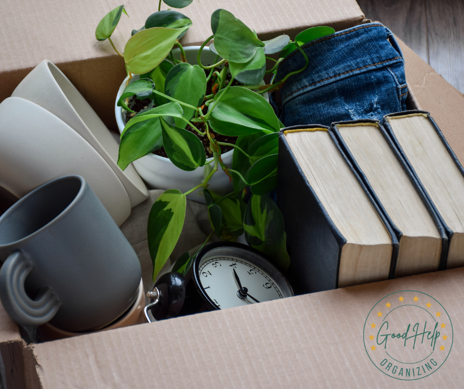 Downsizing box packed with books, dishes, a clock, and a plant.