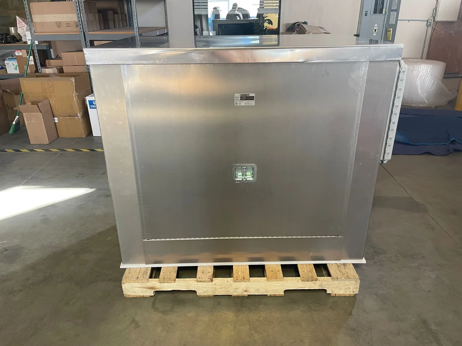 Stainless steel enclosure with hinged access panels, shown in the shop.