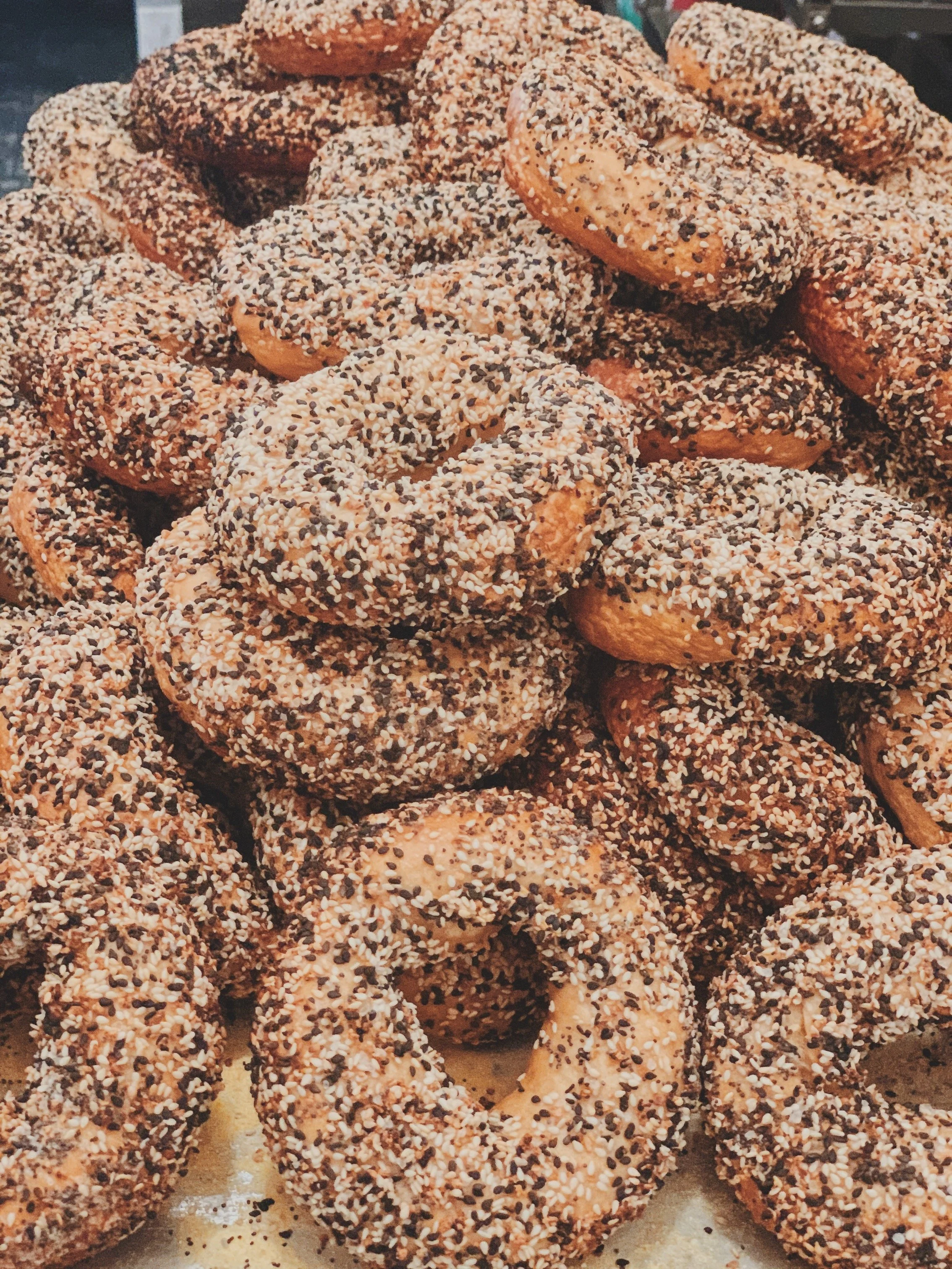 A pile of everything bagels topped with sesame and poppy seeds.