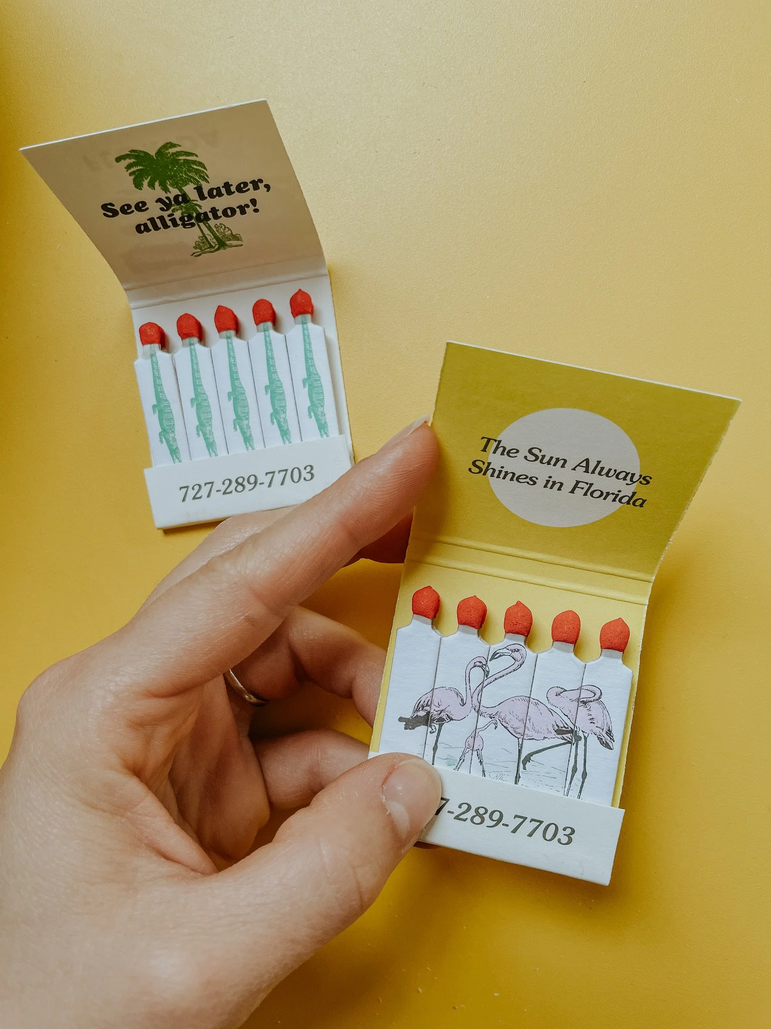 Two opened matchbooks against a yellow background, one with flamingo illustrations and the other with alligator designs and the text 'See ya later, alligator!' and 'The Sun Always Shines in Florida.'"