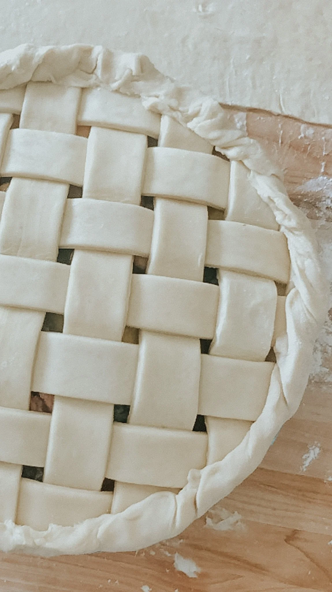 Unbaked pie with a lattice crust on a wooden surface.