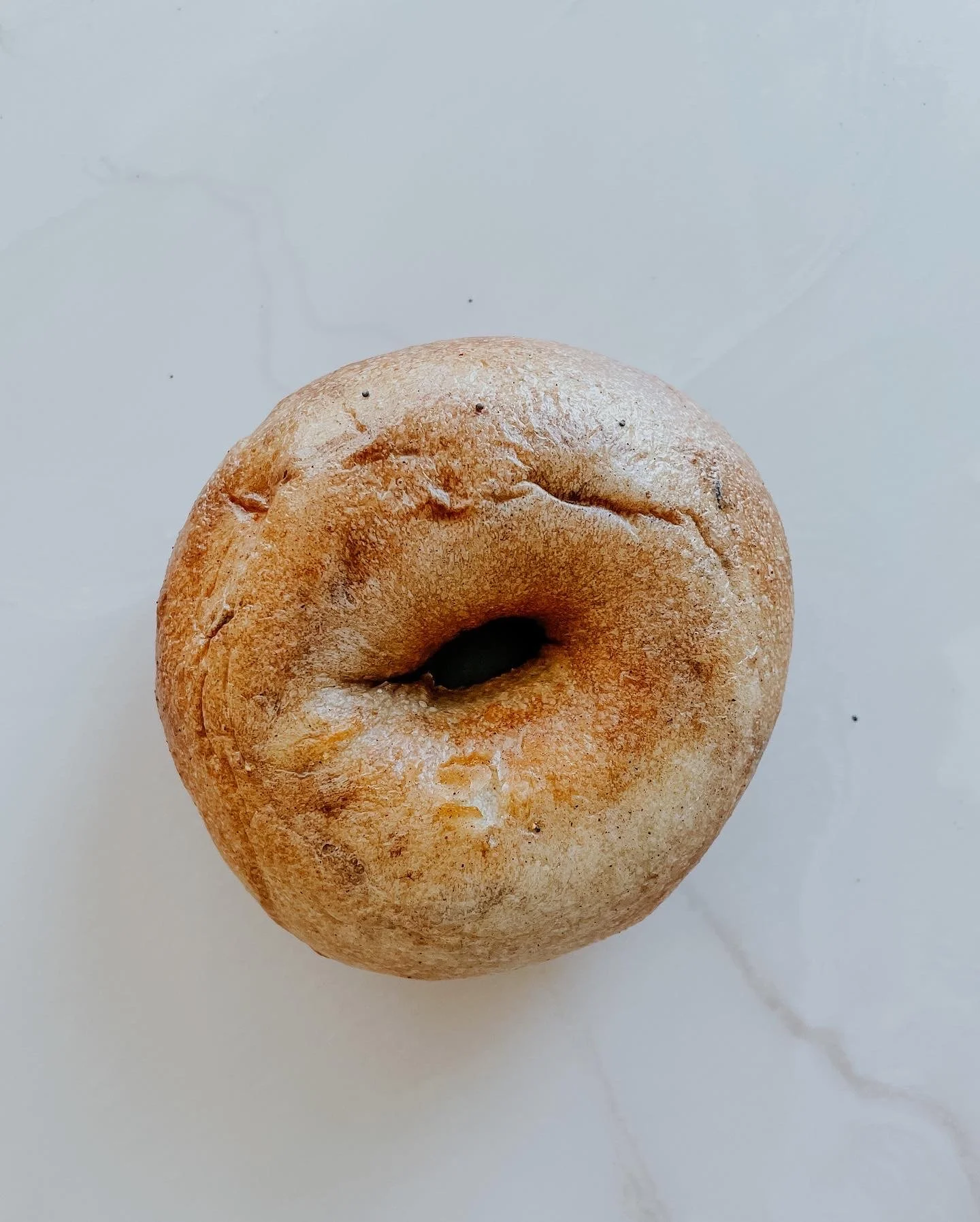 A plain bagel on a white surface.