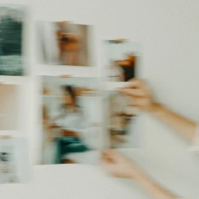 A person flipping through a photo album or picture collection on a white table.