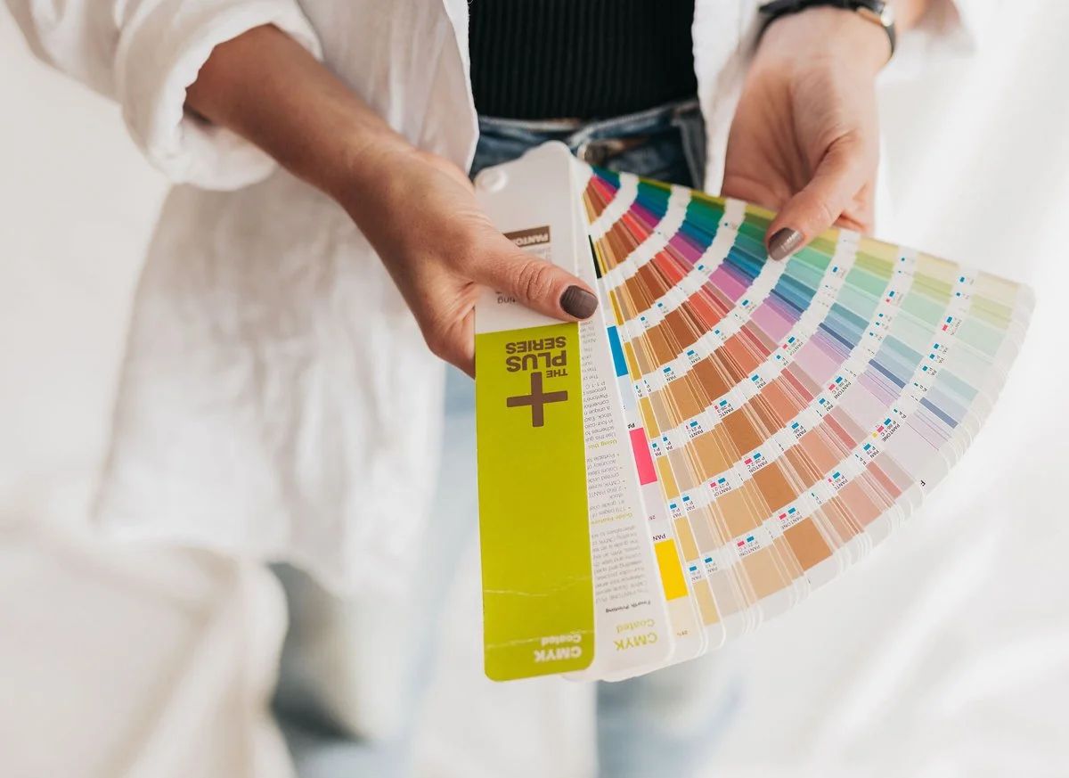 Person holding a color swatch book with ink color samples and a label indicating 'Plus Series'.